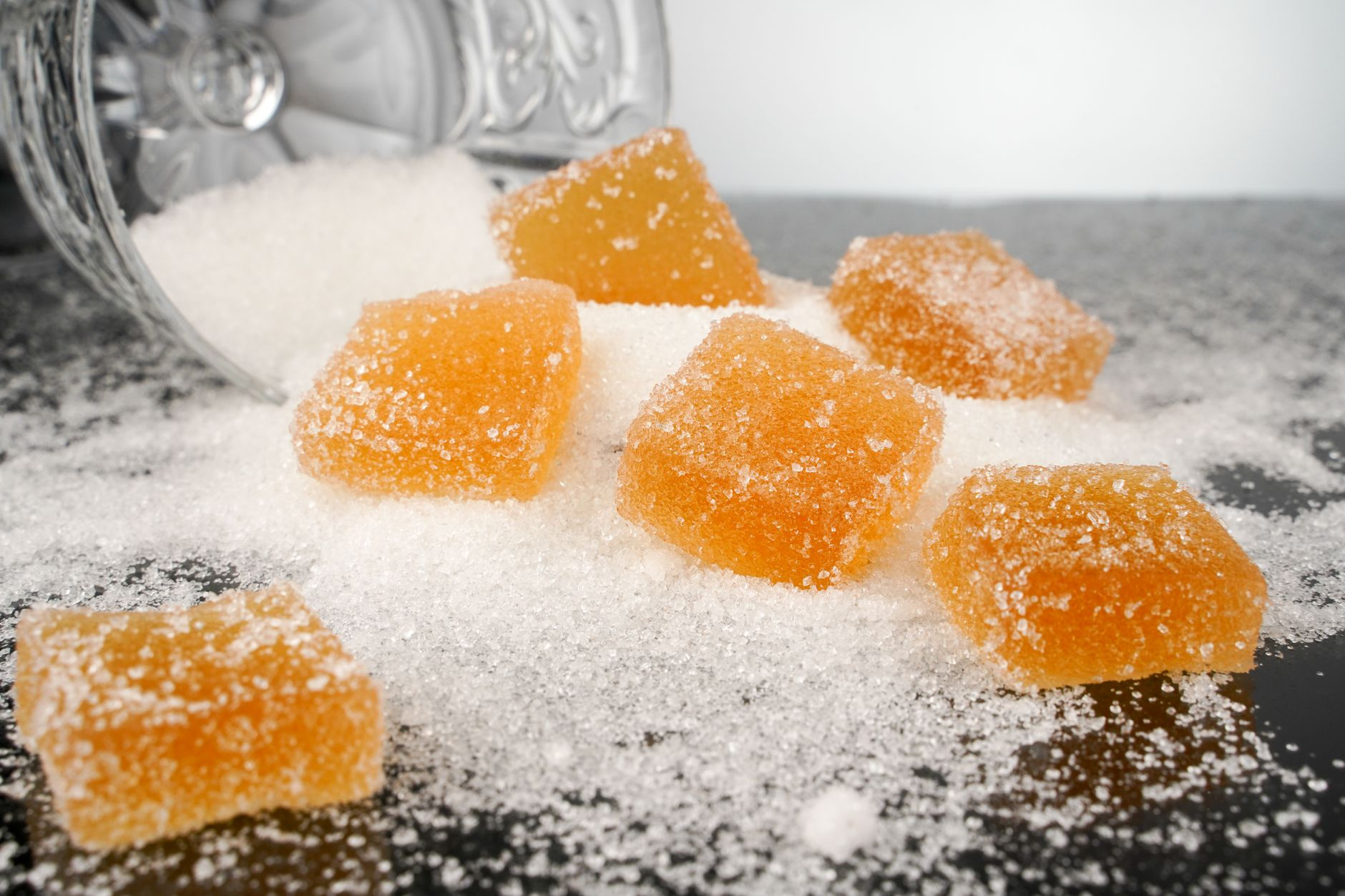 Sugar cubes and sweet packaged snacks beside fresh fruit on a kitchen counter illustrating added versus natural sugar