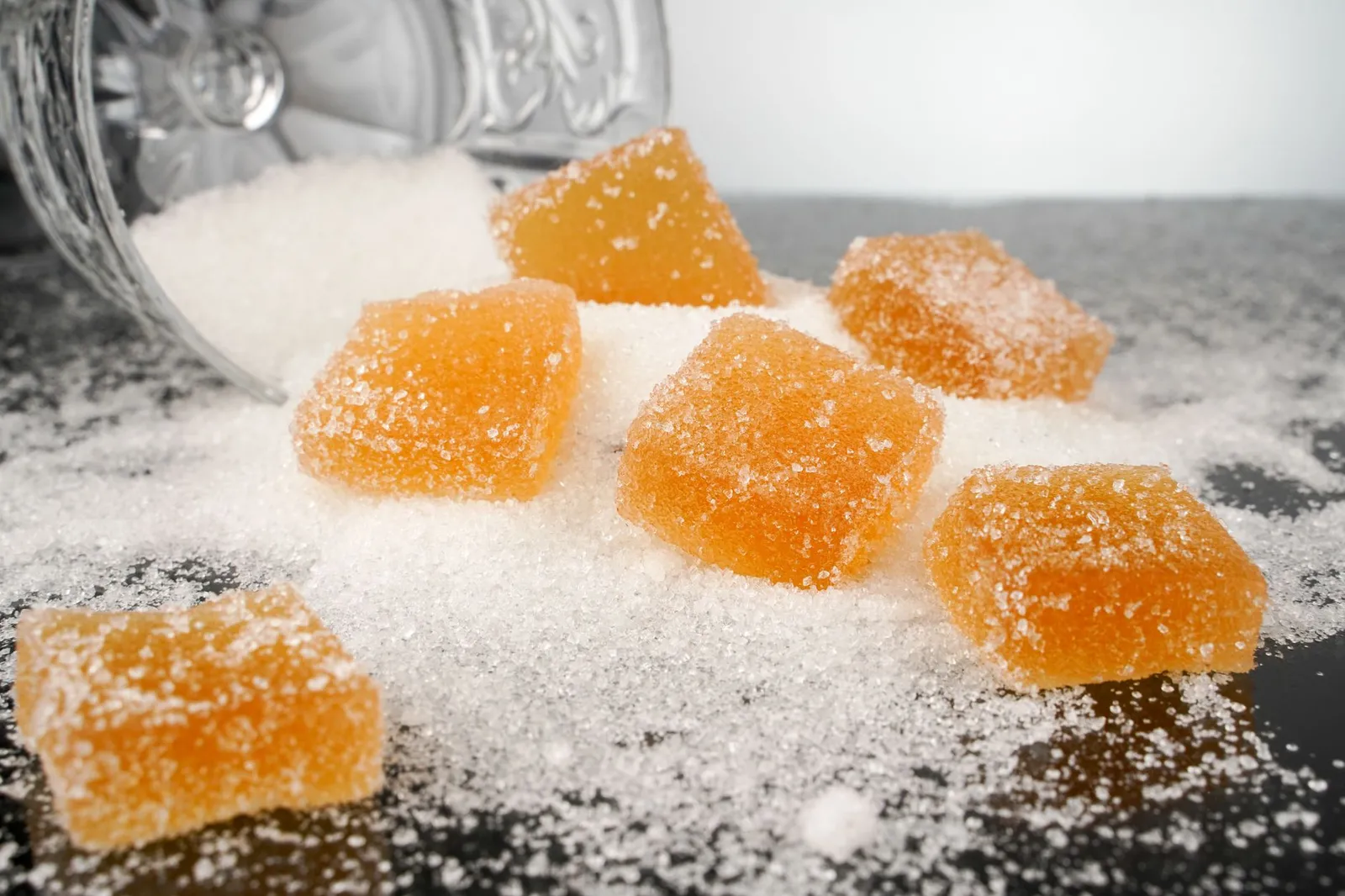 Sugar cubes and sweet packaged snacks beside fresh fruit on a kitchen counter illustrating added versus natural sugar