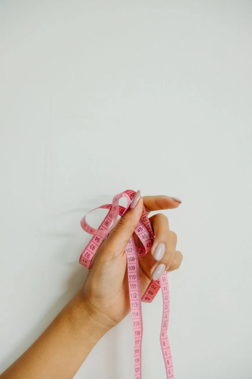A hand holding a pink measuring tape