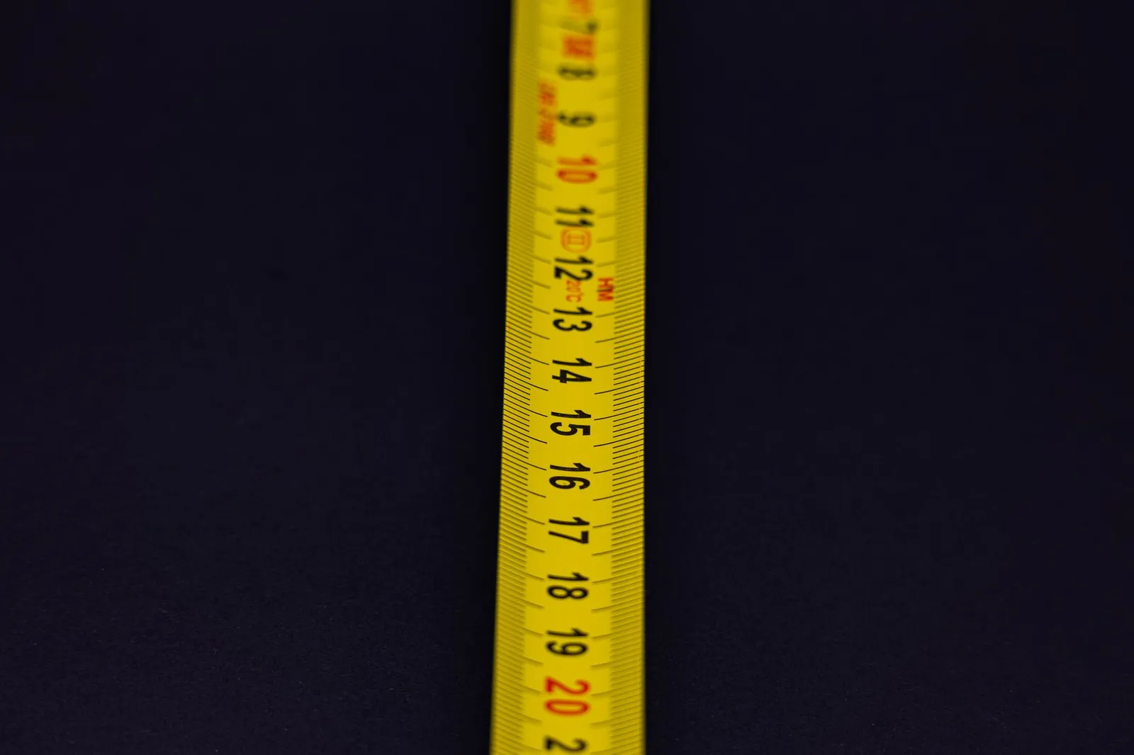 A yellow measuring tape against a dark background
