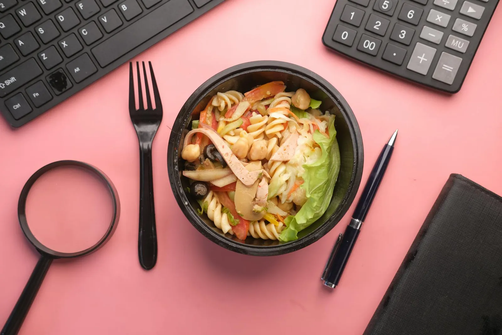 Healthy balanced meal alongside a notebook with calorie calculations and a digital food scale on a kitchen counter