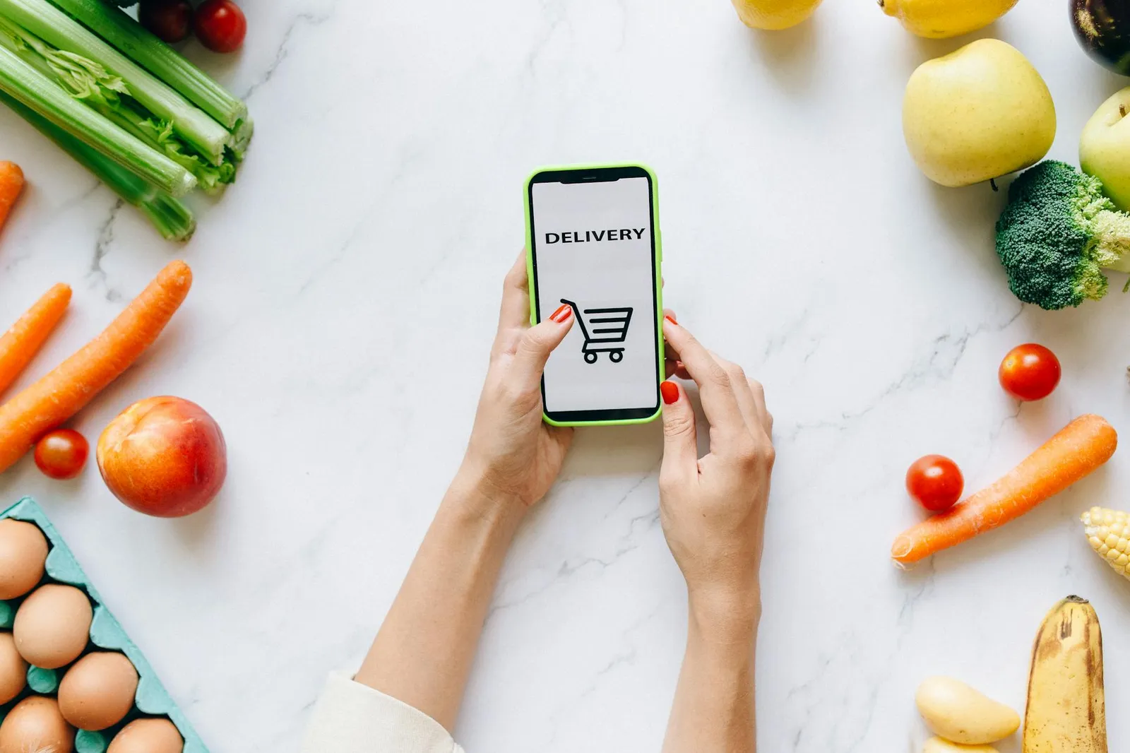 Person reviewing nutrition data on a smartphone while sitting at a kitchen table with a healthy meal