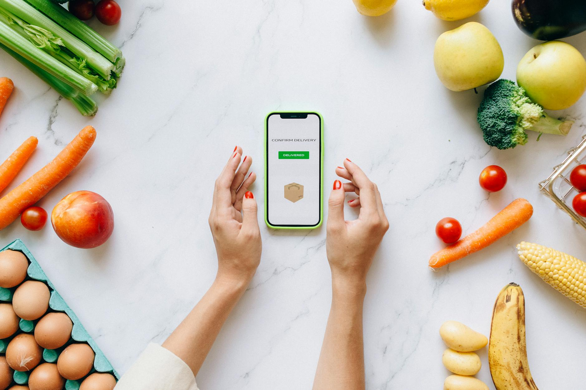 Person checking a smartphone calorie tracking app while eating a healthy mindful meal at a kitchen table with fresh ingredients