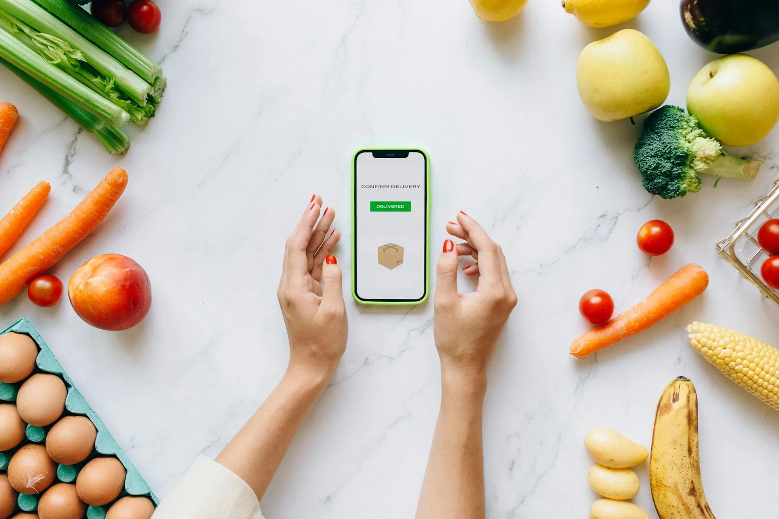 Person checking a smartphone calorie tracking app while eating a healthy mindful meal at a kitchen table with fresh ingredients