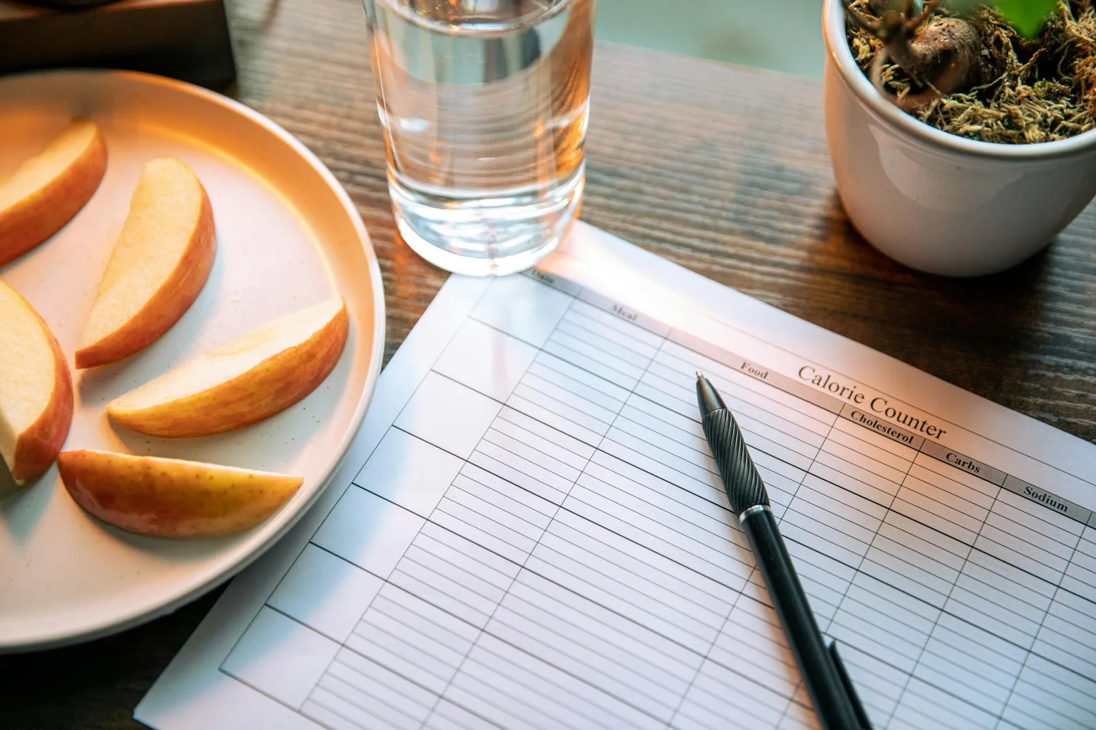 Calm kitchen scene with a notepad showing a hunger scale, a balanced lunch plate, and a glass of water for mindful eating practice