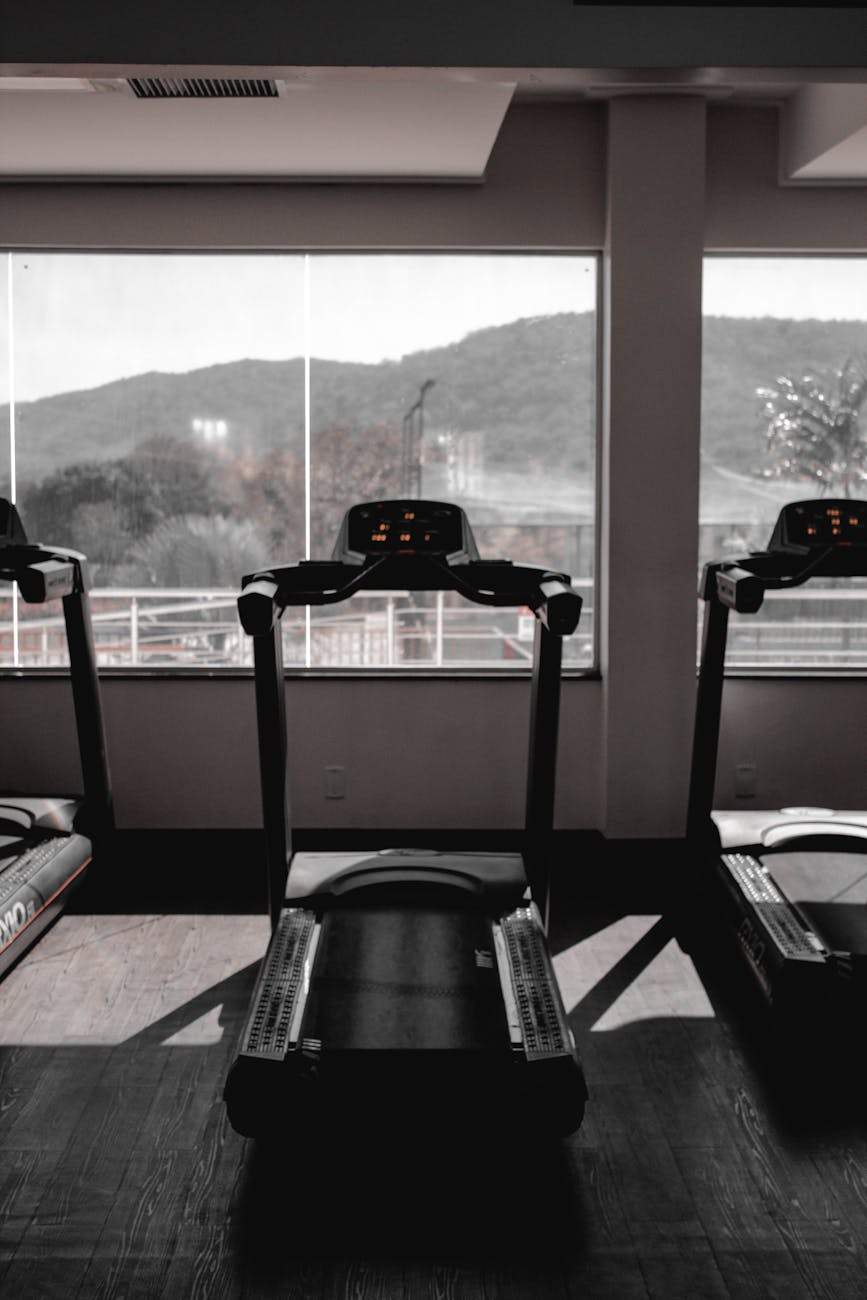 Athletic person finishing a moderate run on a treadmill with a smartwatch display showing heart rate in a bright gym