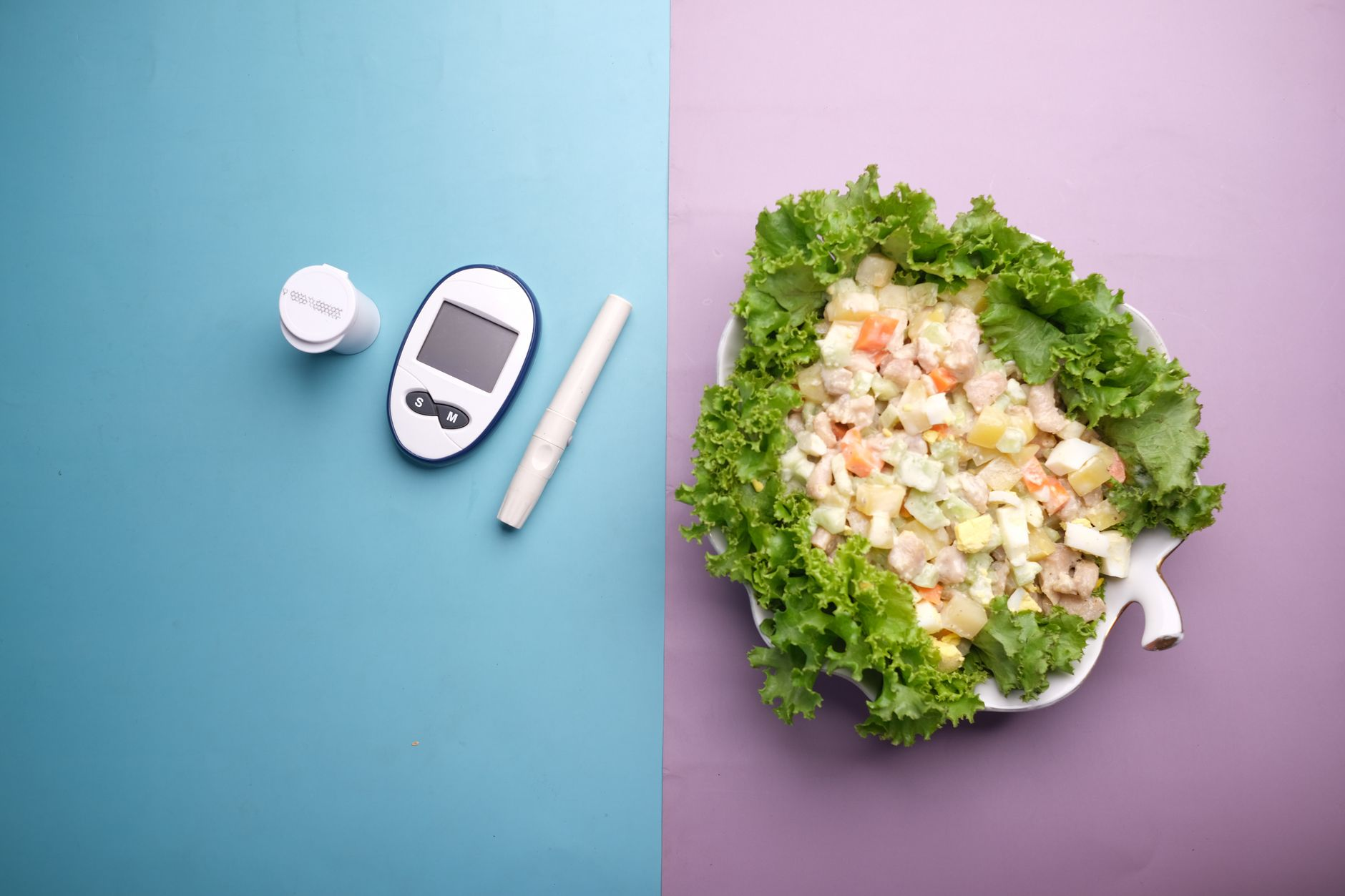 A continuous glucose monitor sensor beside a smartphone showing a calorie tracking app, a digital kitchen scale, and a portioned meal of grilled salmon and quinoa on a sunlit kitchen counter