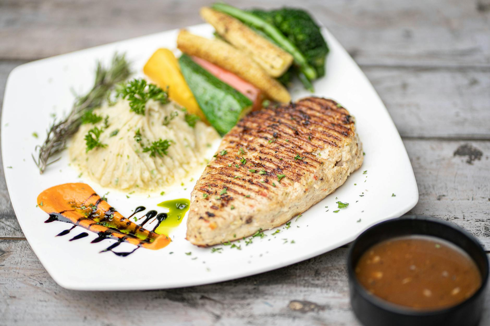 Smartphone showing the ChatGPT app analysing a plated meal of grilled chicken, sweet potato, broccoli, and rice on a sunlit Australian kitchen counter beside a digital scale and a printed nutrition information panel