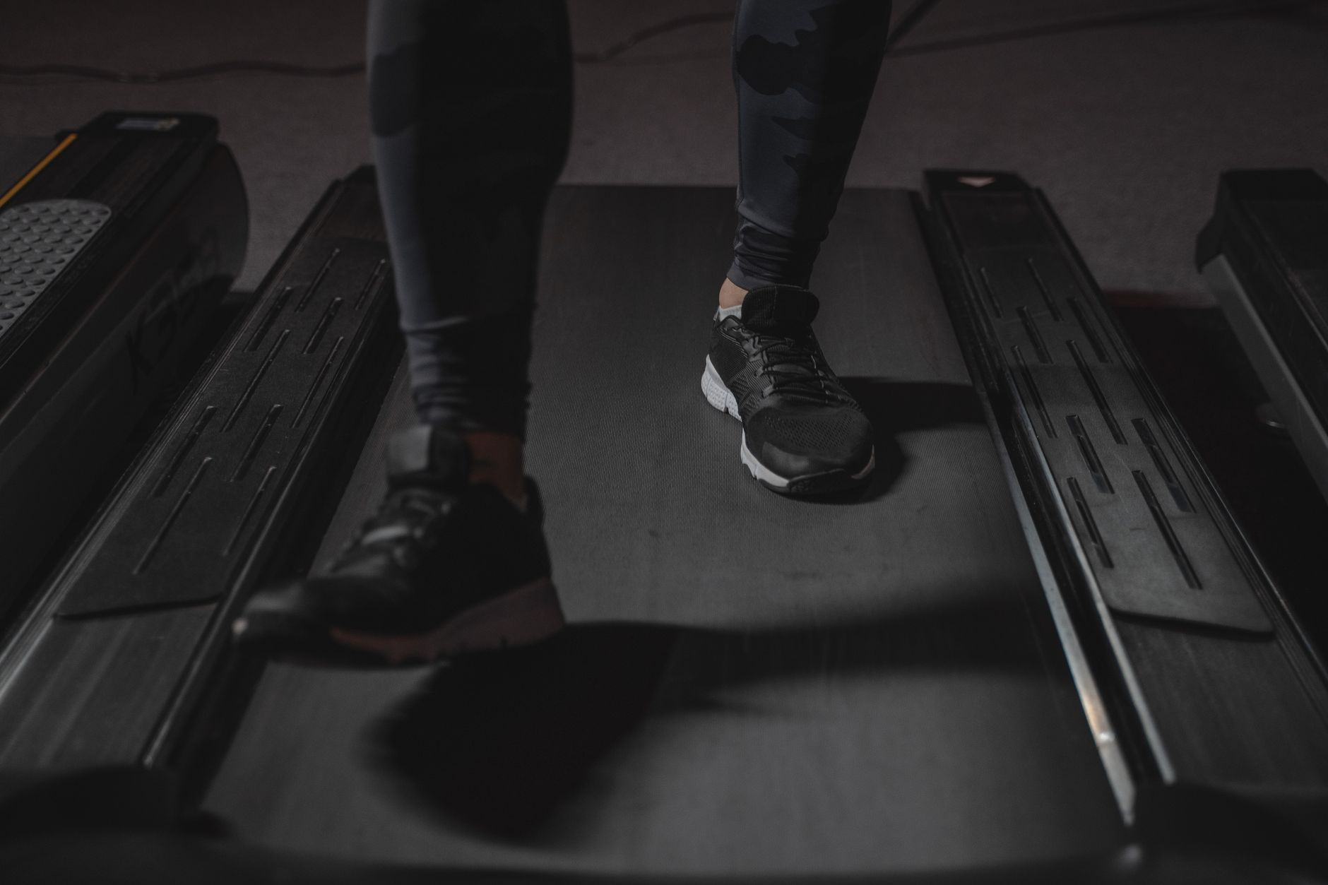 A smartwatch and a treadmill console both showing calorie-burn numbers beside a notebook, illustrating how fitness devices overestimate exercise calories