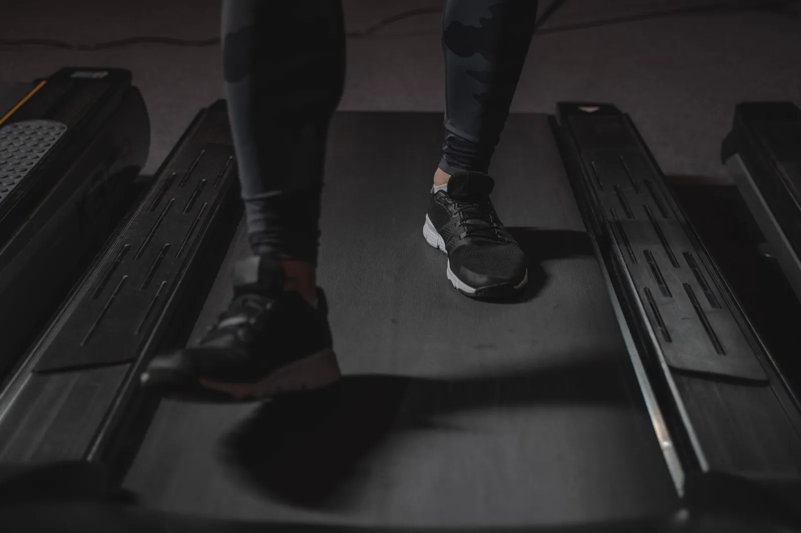 A smartwatch and a treadmill console both showing calorie-burn numbers beside a notebook, illustrating how fitness devices overestimate exercise calories