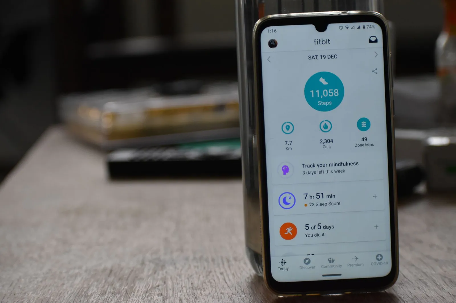 A smartwatch showing an exercise calorie burn beside a calorie tracking app on a phone, a bowl of food, and a notebook on a sunlit kitchen counter, illustrating whether to eat back exercise calories