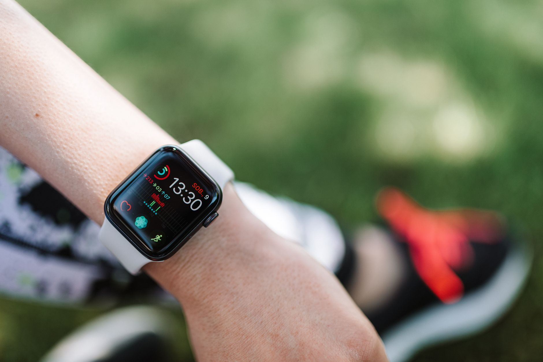 A fitness watch on a wrist displaying a fat-burn heart-rate zone beside a treadmill console showing a calorie readout in a sunlit gym, illustrating where the fat-burning zone label comes from
