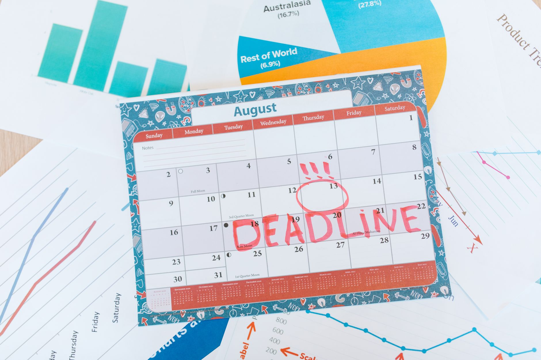 A bathroom scale beside a wall calendar marked with daily weigh-ins and a notebook of weekly averages in a sunlit bathroom