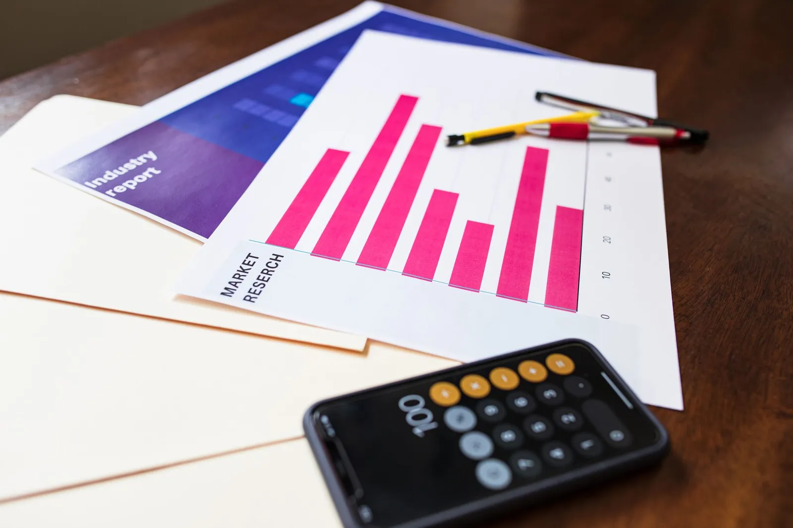 An open food diary with daily calorie totals beside a bathroom scale, a calculator, and a smartphone showing a weight-trend graph on a sunlit kitchen counter, illustrating how to calculate real TDEE from your own tracking data