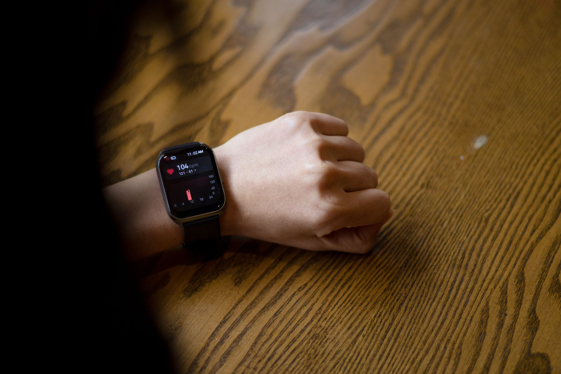 A smartphone food log open beside a smartwatch showing a heart-rate zone and a notebook with a weekly weight trend on a sunlit kitchen table, illustrating intake-anchored tracking