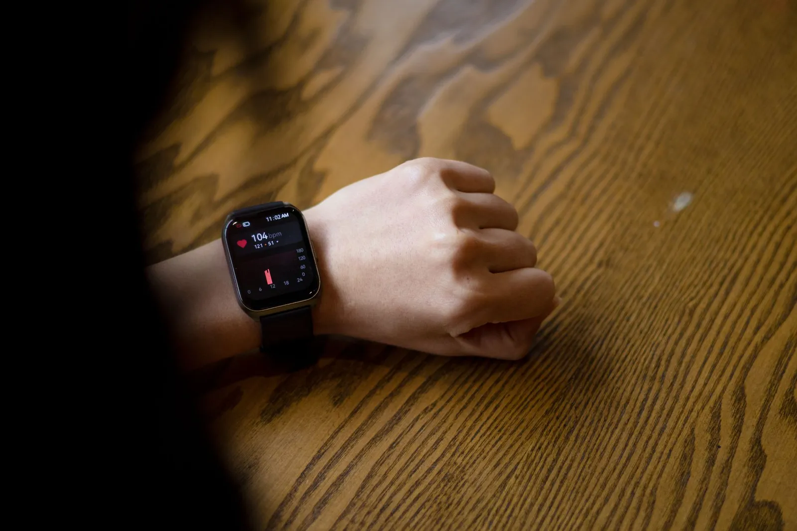 A smartphone food log open beside a smartwatch showing a heart-rate zone and a notebook with a weekly weight trend on a sunlit kitchen table, illustrating intake-anchored tracking