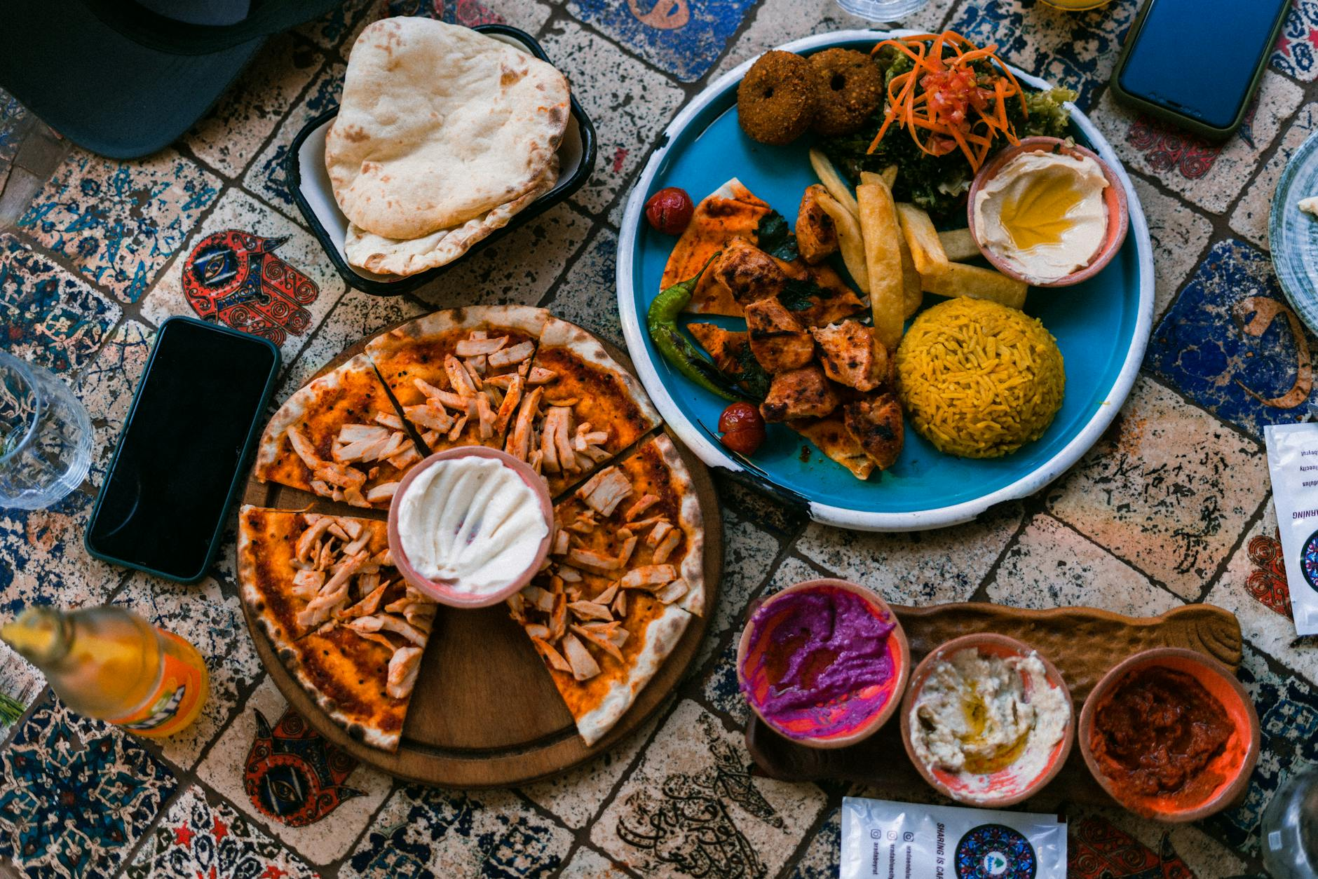 Colorful variety of foods including pizza, fruit, grilled chicken, and vegetables arranged together on a table