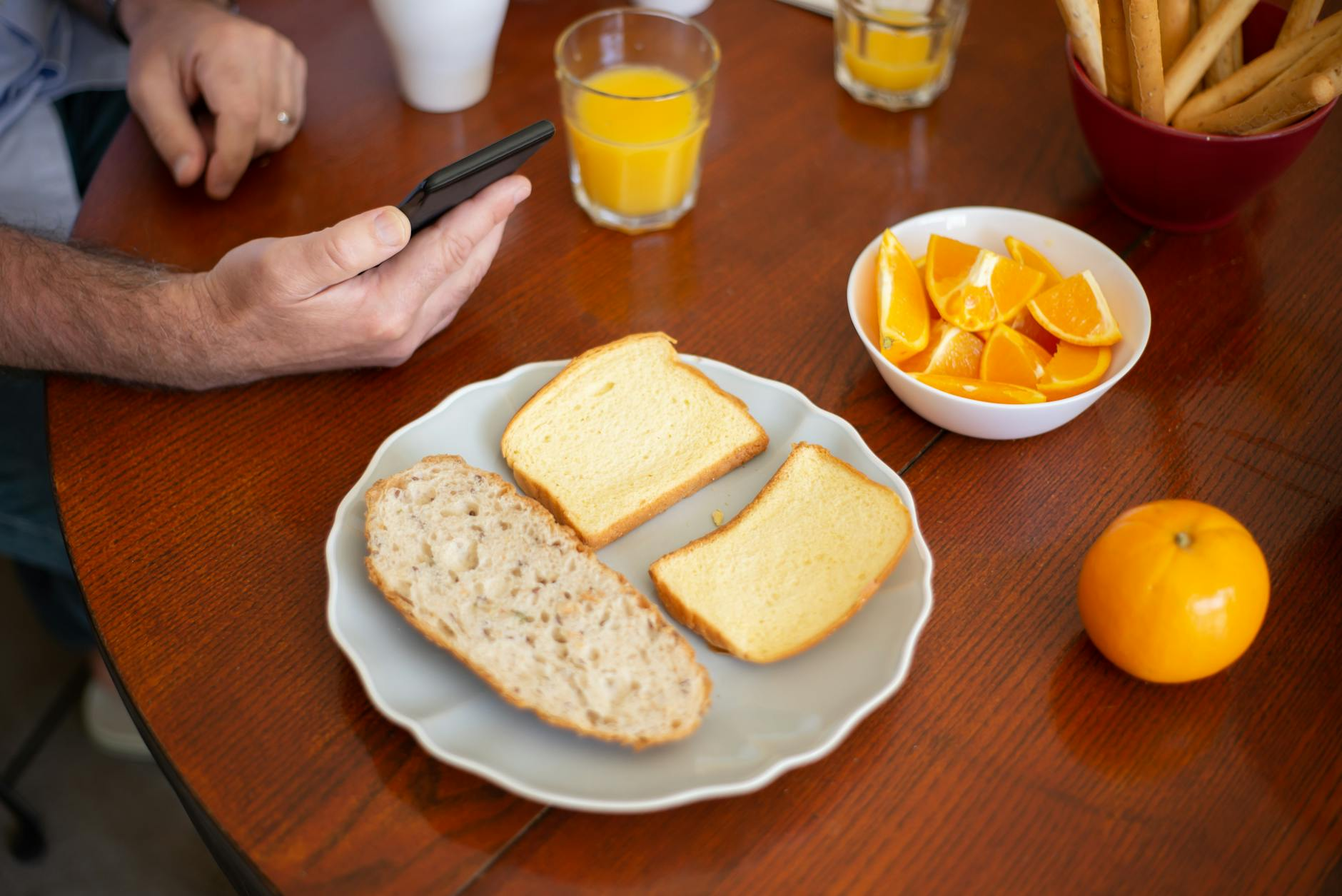 Person setting up a calorie tracking app on their smartphone at a bright kitchen table with a healthy breakfast