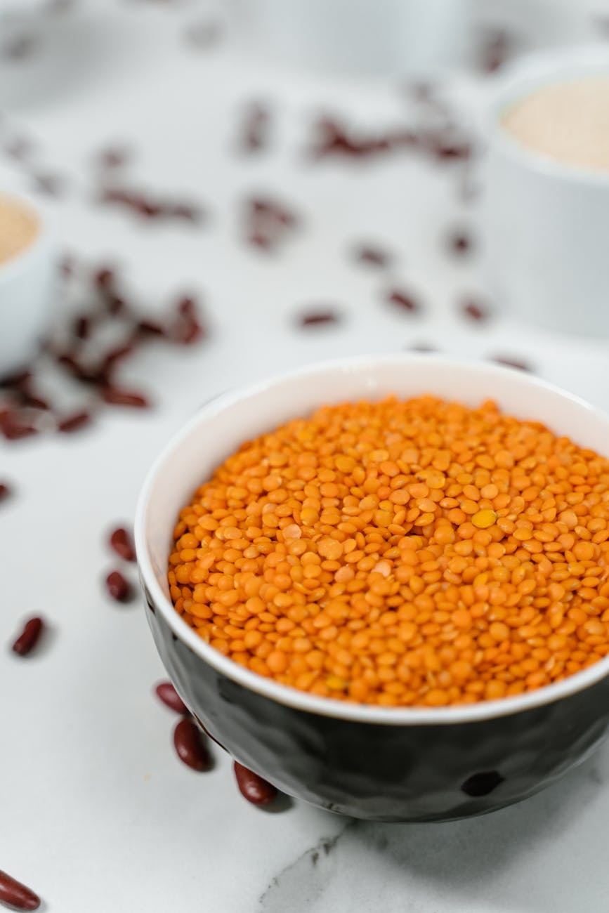 Affordable budget-friendly proteins including eggs, lentils, canned beans, chicken thighs, and peanut butter on a kitchen counter
