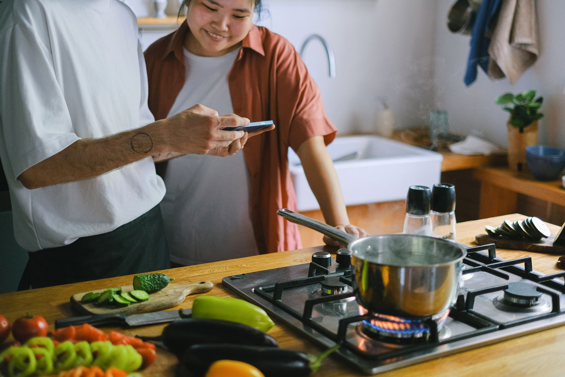 HelloFresh meal kit ingredients — chicken breast, fresh vegetables, herbs, and the recipe card — spread across a sunlit Australian kitchen counter beside a kitchen scale and a smartphone showing a calorie tracking app