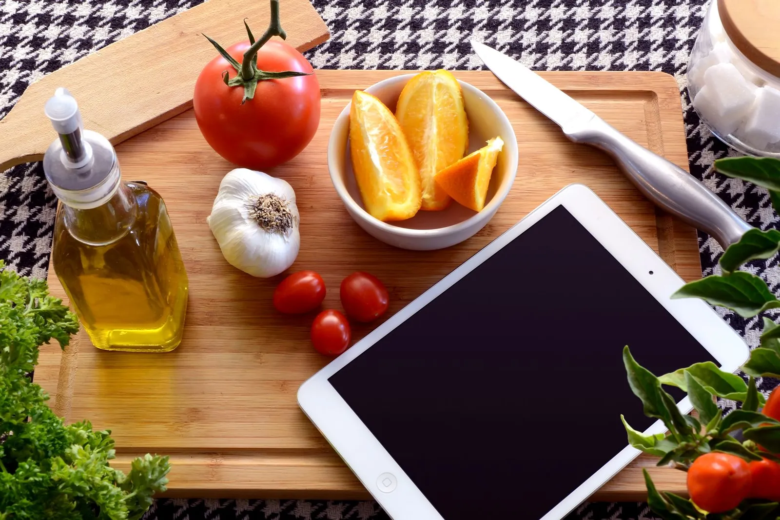 A digital kitchen scale weighing raw chicken and chopped vegetables beside a bottle of cooking oil, a wok, and a smartphone showing a calorie tracking app on a sunlit kitchen counter, illustrating how to count calories in a homemade meal