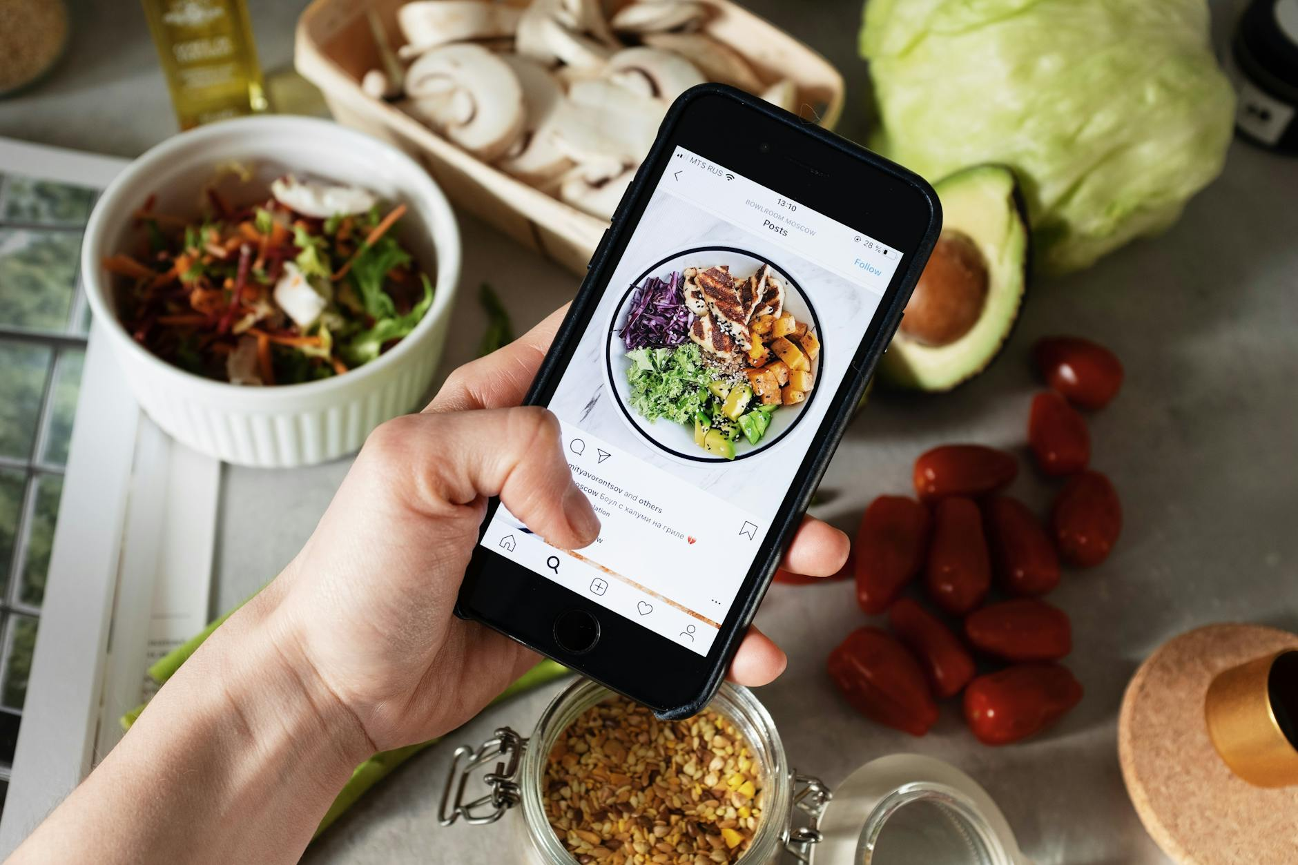 Smartphone analyzing a plated meal with AI-generated nutrition overlay in a bright kitchen with fresh vegetables and fruit