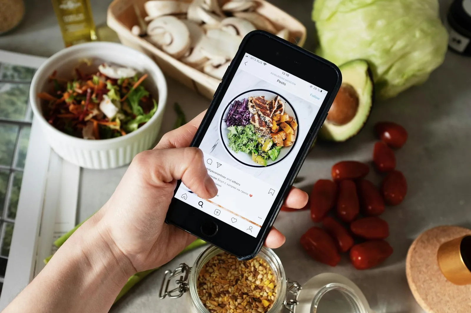 Smartphone analyzing a plated meal with AI-generated nutrition overlay in a bright kitchen with fresh vegetables and fruit