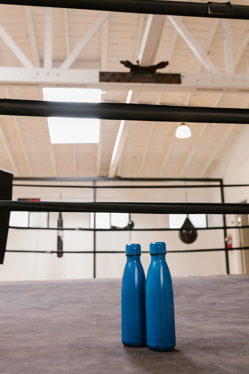 Reusable water bottle and a fitness towel on a gym mat to illustrate hydration during exercise and workouts