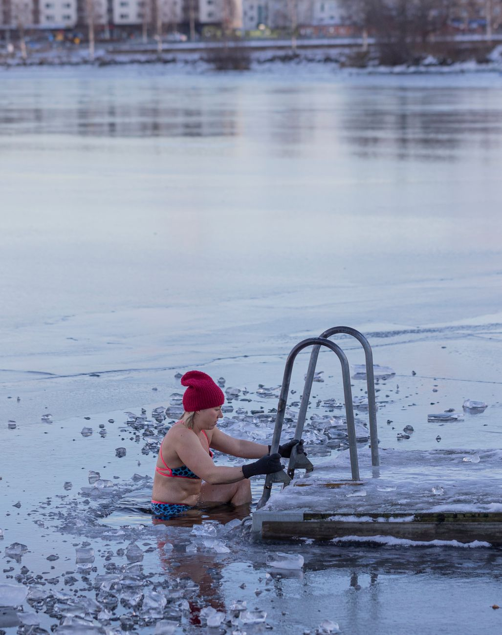 A person easing into an outdoor ice bath barrel surrounded by winter light, illustrating the modest measured energy cost of a typical cold plunge session