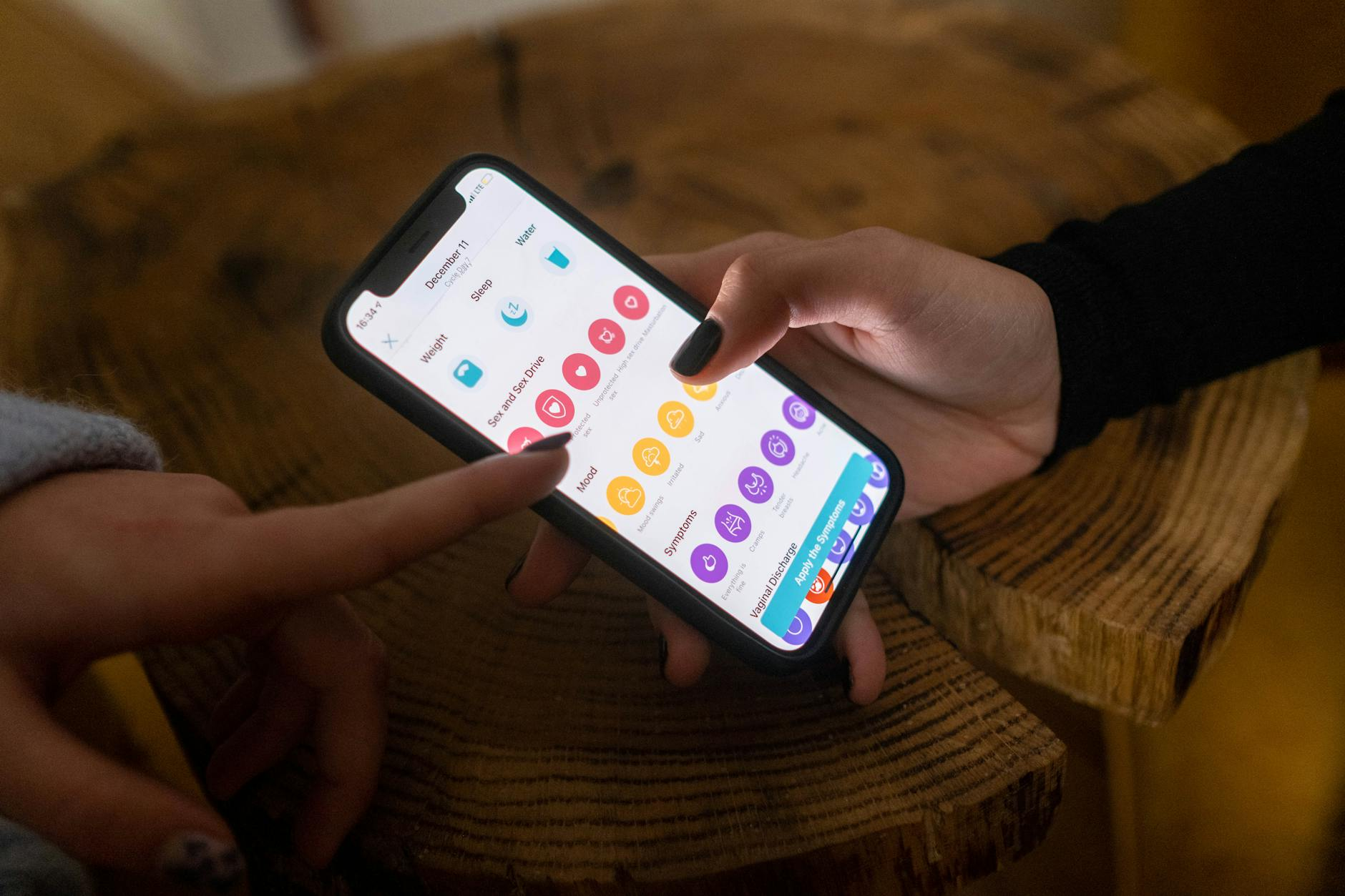 Person checking a meal tracking app on their smartphone at a dining table with a balanced meal during their eating window