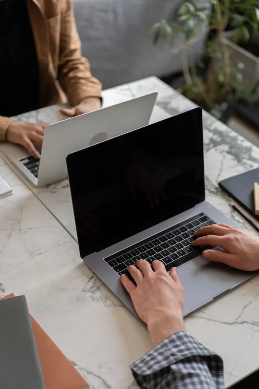 Two people using laptops at a shared table