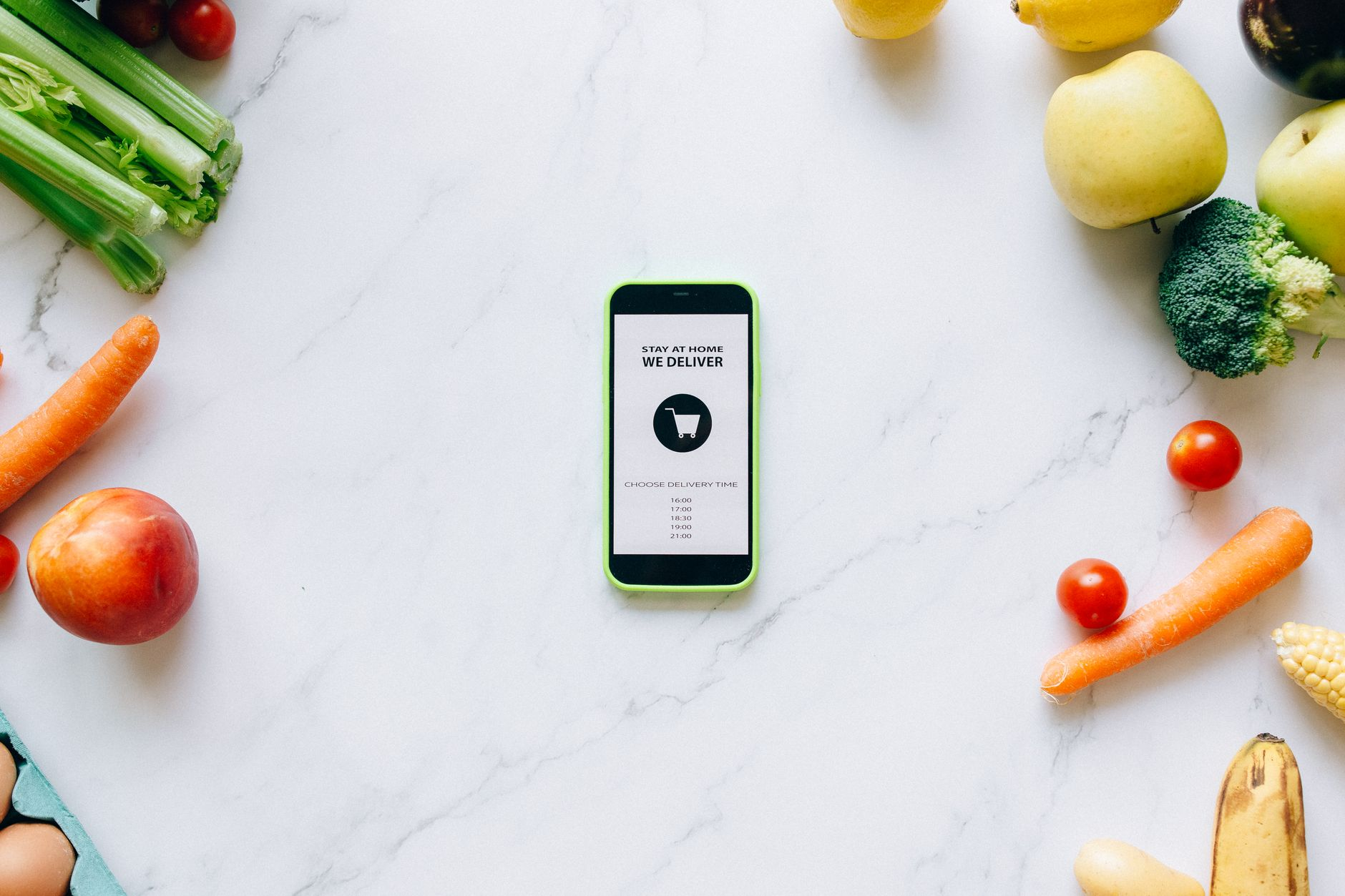 Smartphone screen showing a calorie tracking app dashboard beside a digital kitchen scale weighing a portioned serve of chicken breast on a sunlit kitchen counter with fresh vegetables nearby