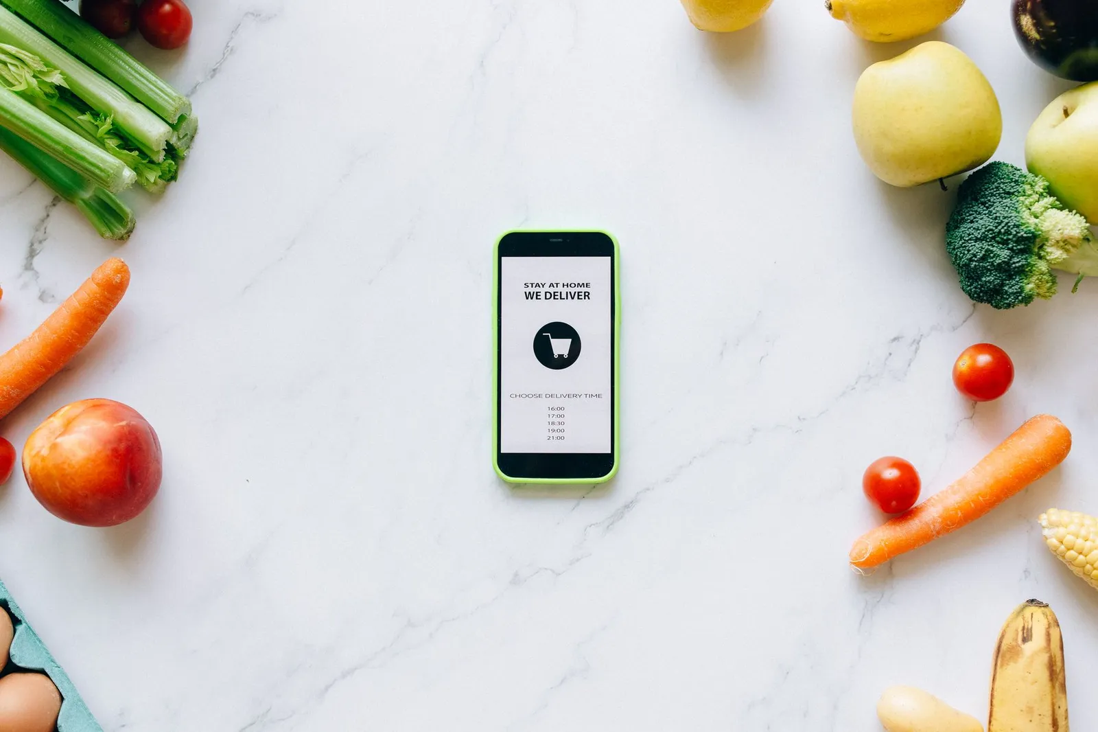 Smartphone screen showing a calorie tracking app dashboard beside a digital kitchen scale weighing a portioned serve of chicken breast on a sunlit kitchen counter with fresh vegetables nearby