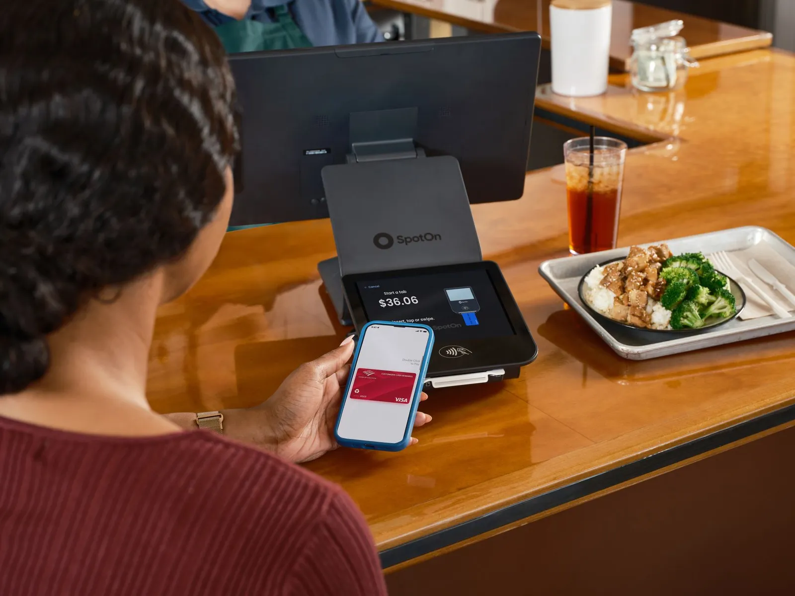 Two smartphones side by side on a sunlit kitchen counter showing different calorie tracking app interfaces beside a digital kitchen scale, a printed nutrition information panel, and a portioned meal of grilled chicken, brown rice, and steamed broccoli