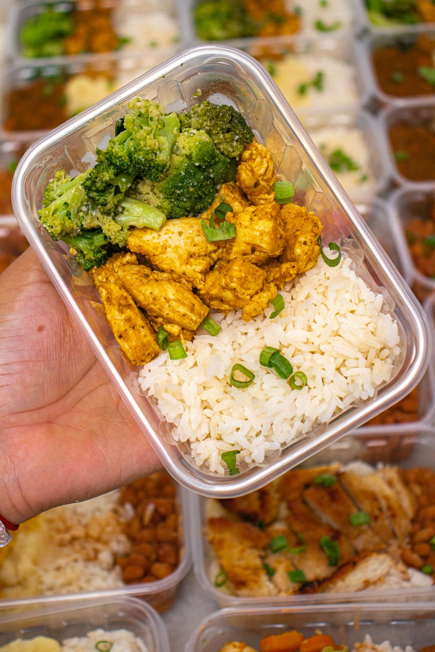 Gym setting with a post-workout protein shake, dumbbells, and a meal prep container with chicken and rice