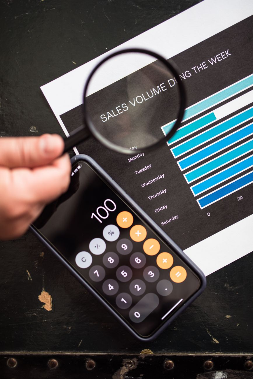 A close-up of a packaged food nutrition information panel beside a magnifying glass and a calculator on a sunlit kitchen counter, illustrating the legal tolerance around calorie labels