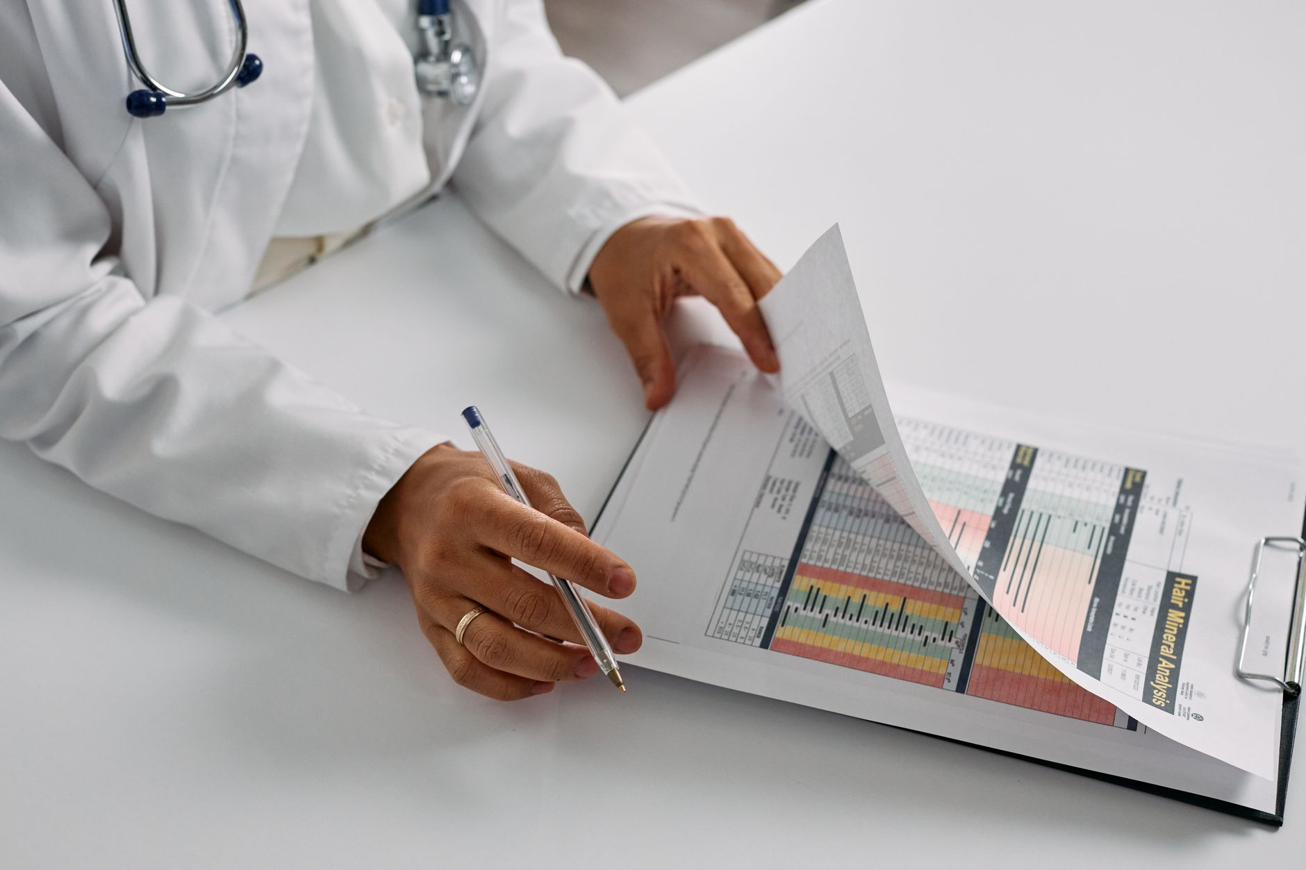 A printed organ-by-organ metabolism table beside a stethoscope, a calculator, and a glass of water on a sunlit desk, illustrating how the heart, brain, and liver dominate resting calorie burn per kilogram