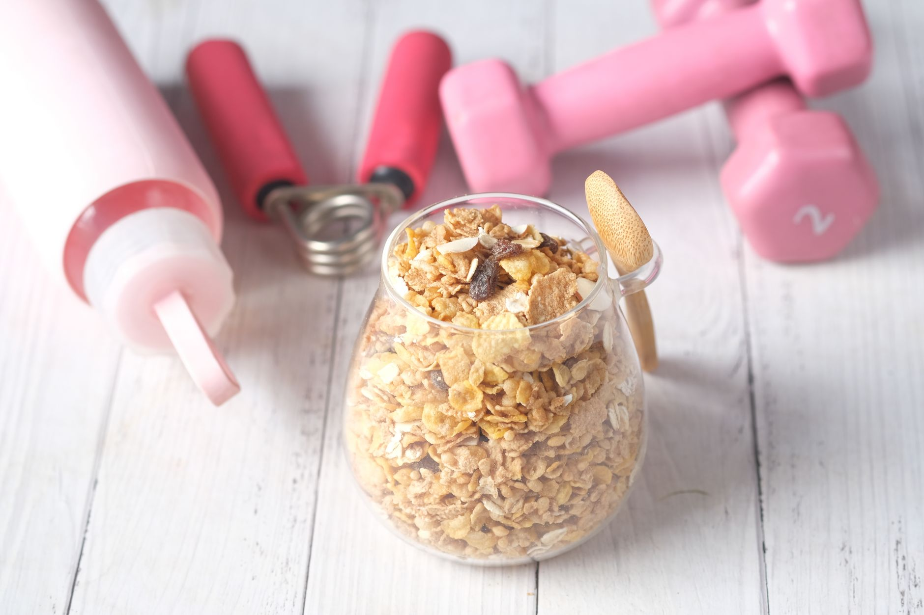 A food diary open beside a dumbbell, a protein-rich meal of grilled chicken and yoghurt, and a smartphone showing a weight-trend graph on a sunlit kitchen table, illustrating how to fold muscle gain into a calorie target