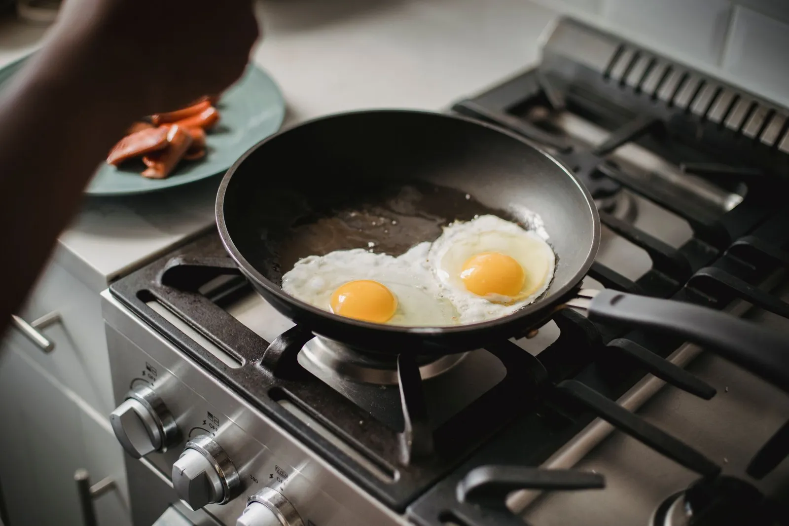 A plate of grilled chicken, eggs, and yoghurt beside a printed study summary and a calculator on a sunlit kitchen counter, illustrating the dose-response studies behind the 30 g protein per meal myth