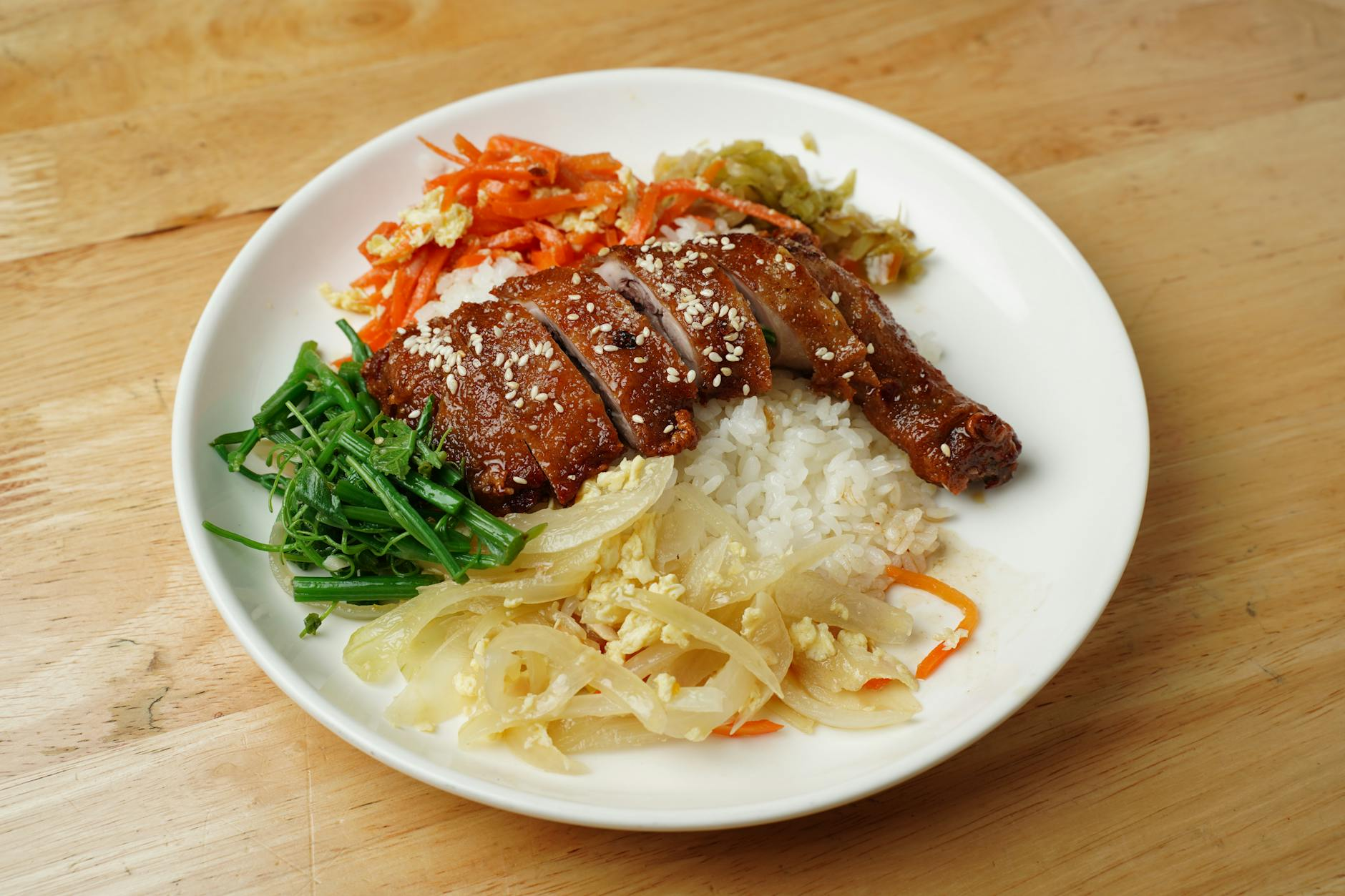 Person tracking weekly weight average and daily calories on a smartphone alongside a balanced meal with chicken, rice, and vegetables on a kitchen table