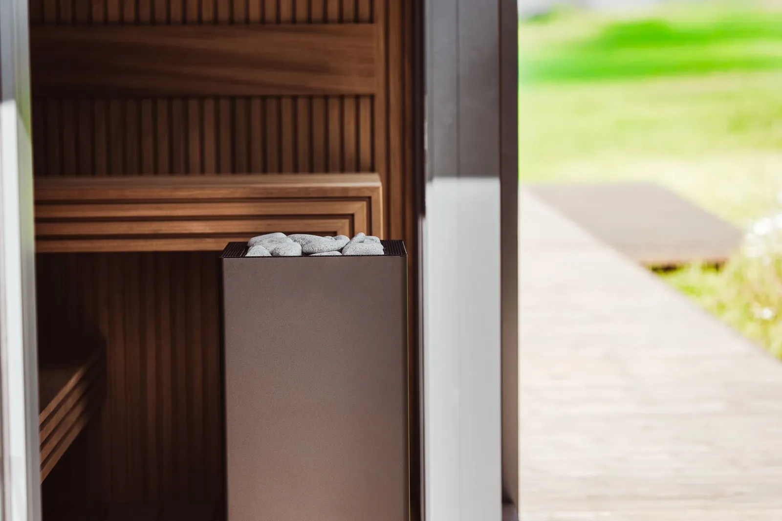 A stone-filled sauna heater beside wooden panelling and a glass doorway