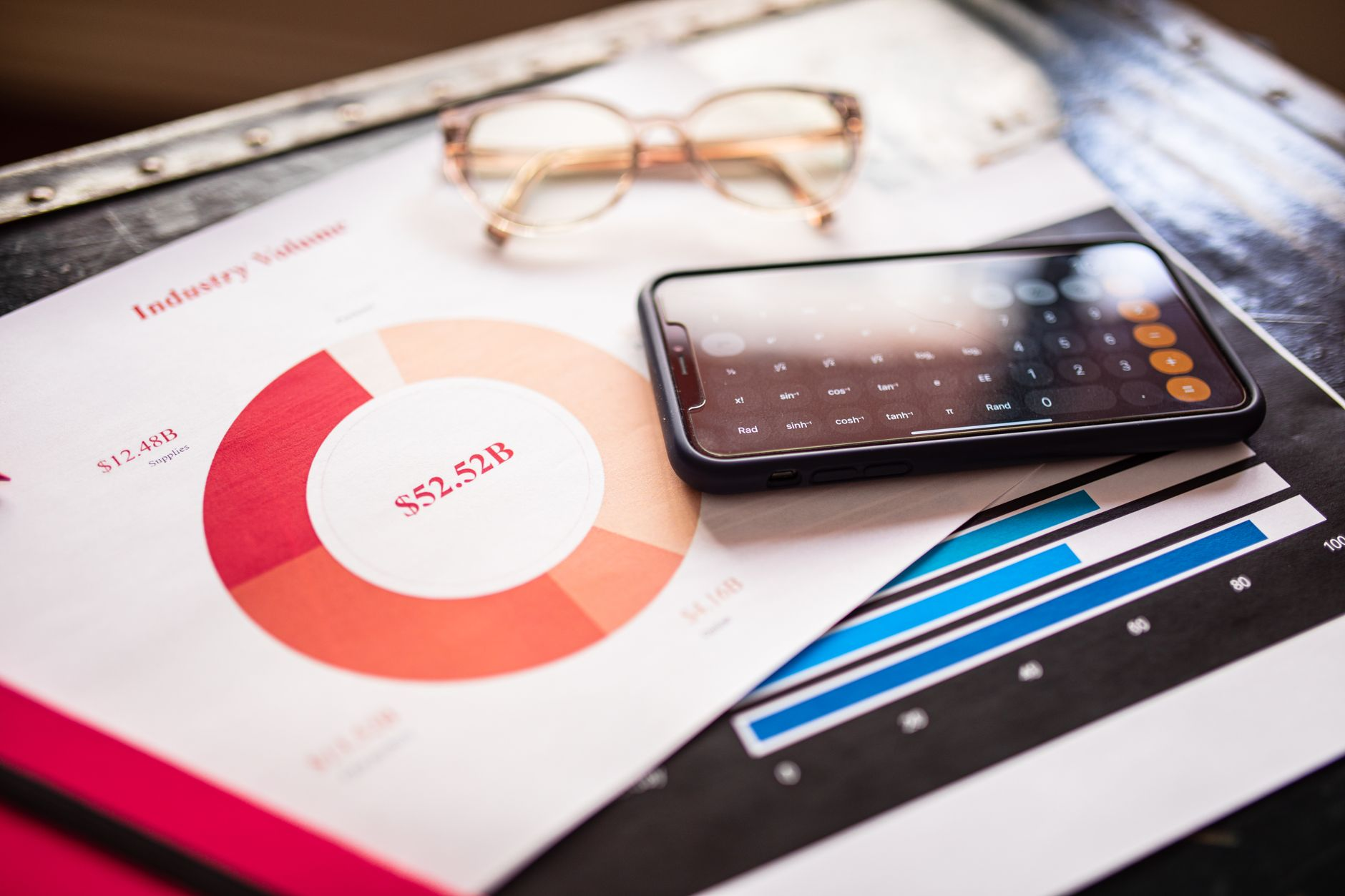 An open notebook showing a weekly weight-trend line smoothing out daily spikes, beside a bathroom scale and a smartphone weight graph in soft morning light