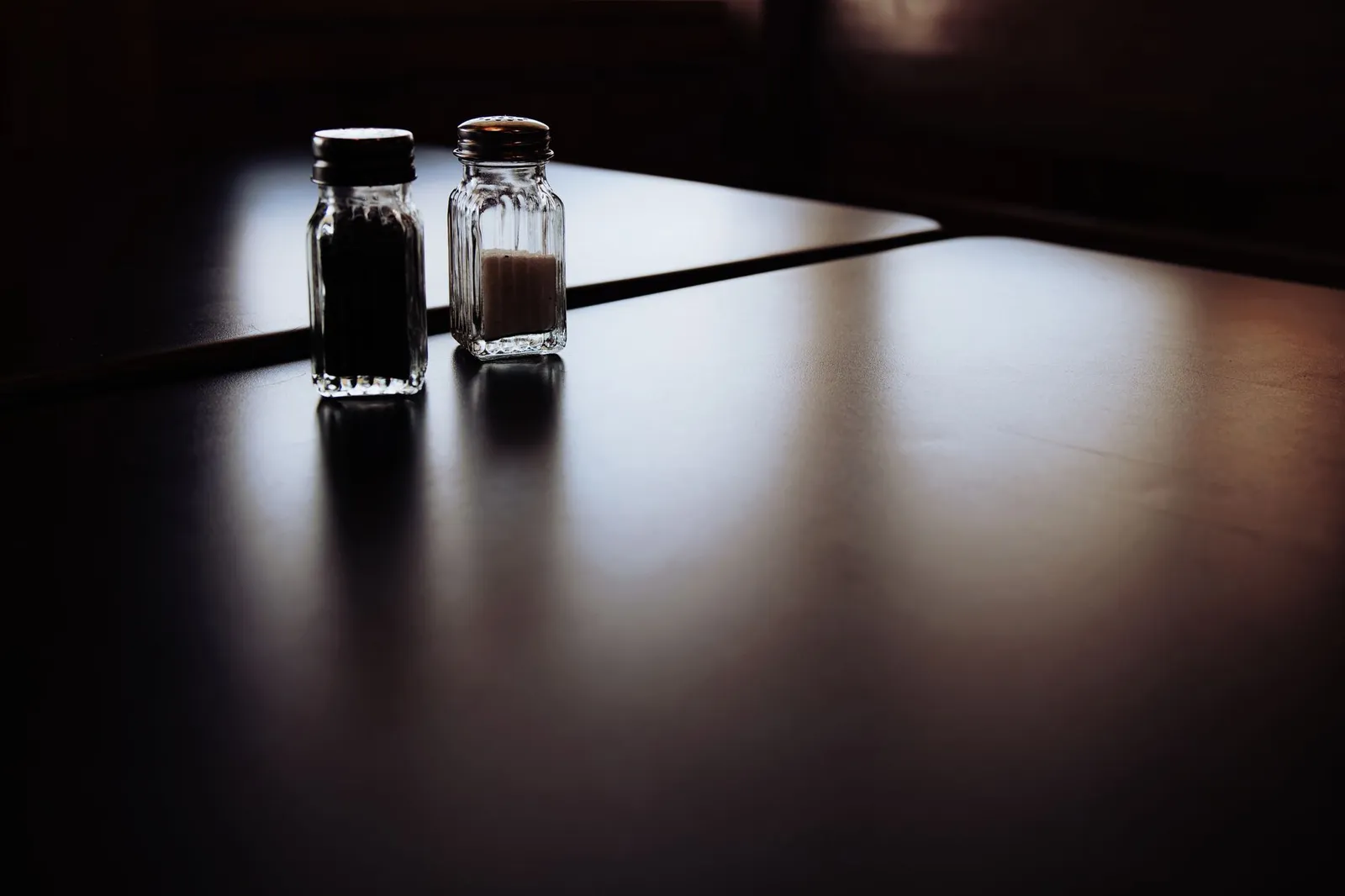 A bathroom scale beside a glass of water, a salt shaker, and a bowl of cooked rice on a sunlit bathroom floor, illustrating the water-weight causes behind an overnight jump in scale weight