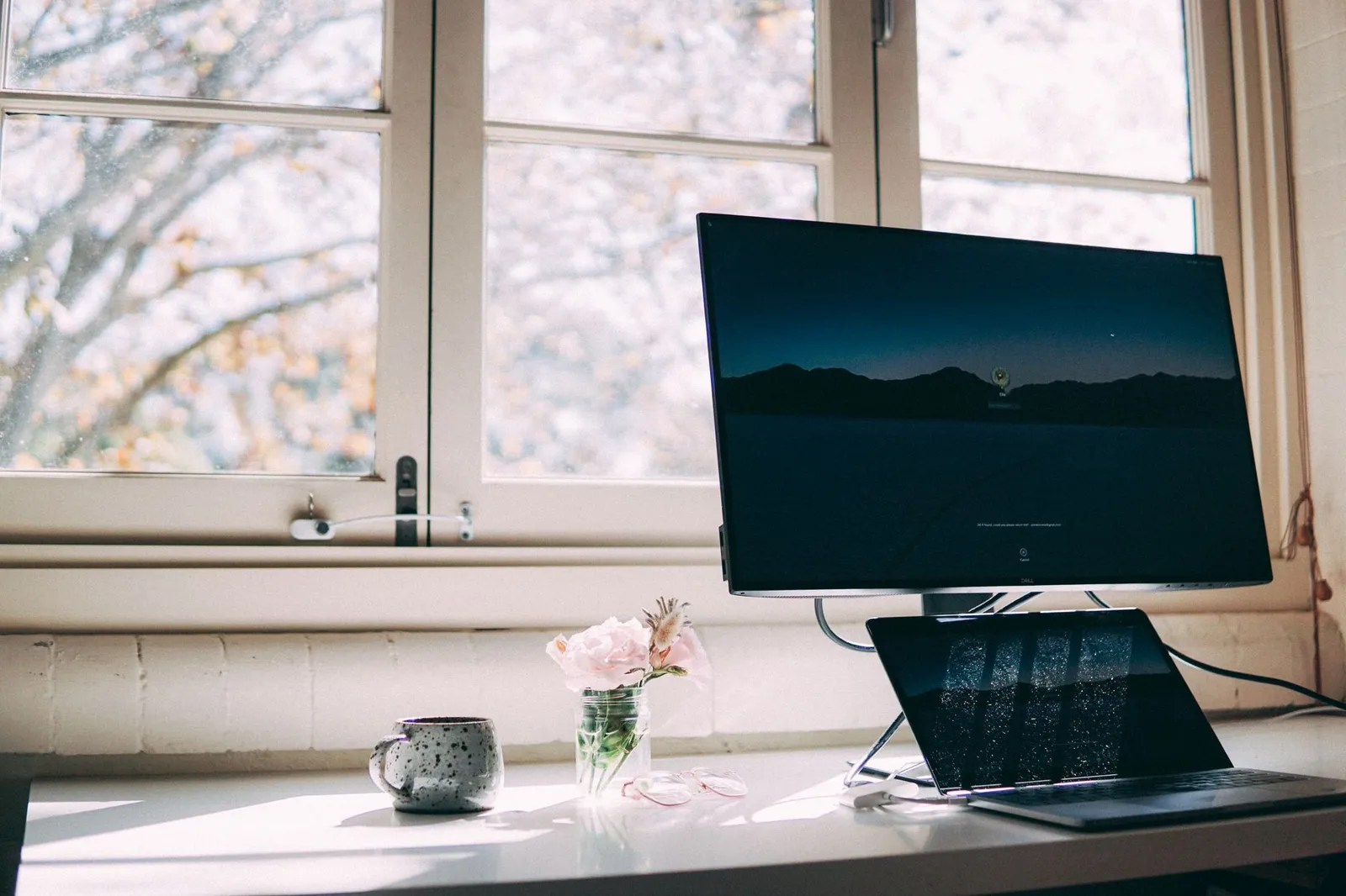 A person working at a height-adjustable standing desk in a bright home office beside a smartphone showing a calorie tracking app, illustrating the small measured calorie difference between sitting and standing