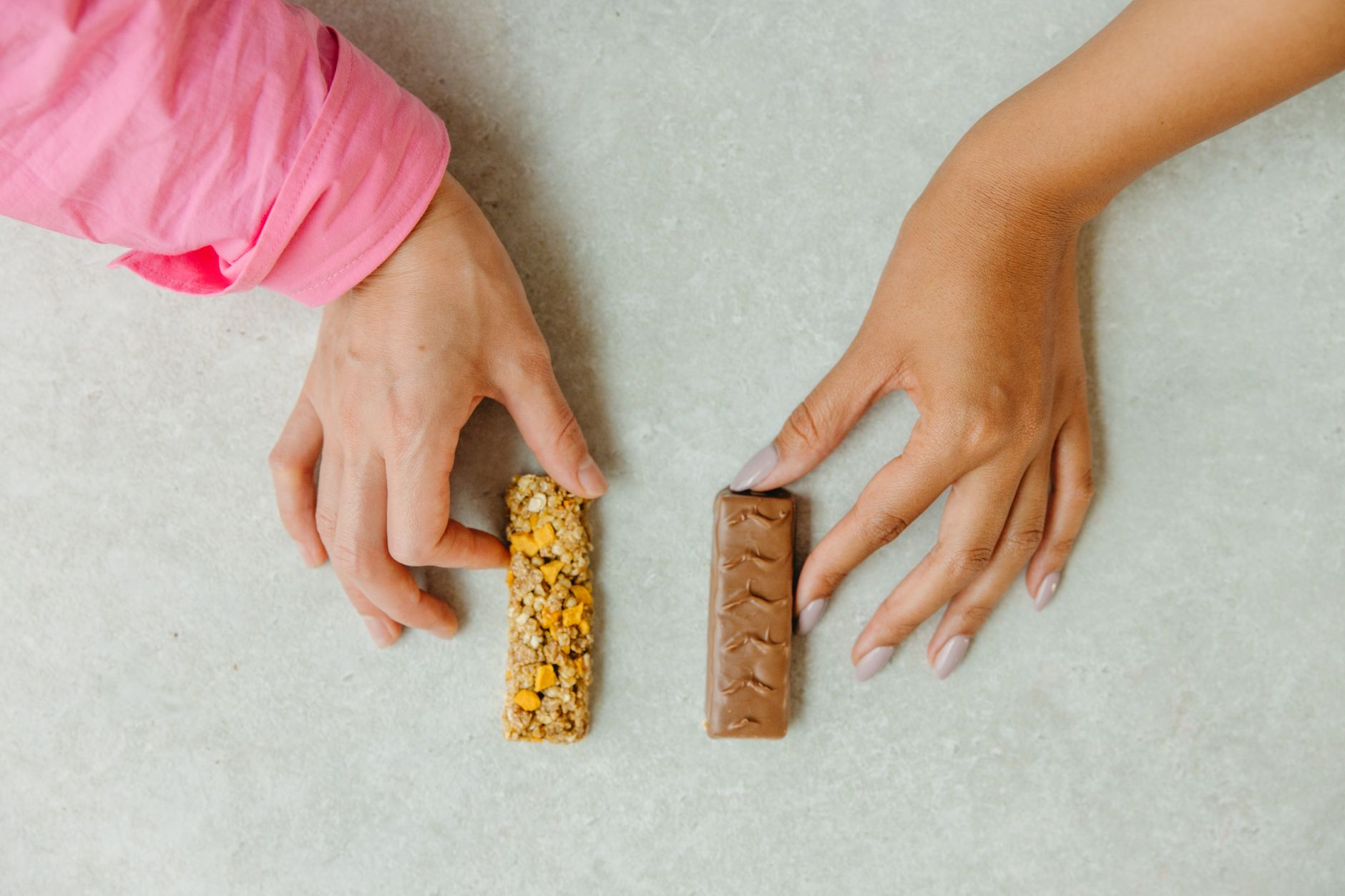 A person comparing a zero-sugar chocolate bar and a regular chocolate bar side by side with their nutrition panels beside a calorie tracking app, illustrating that the sugar-free version still carries most of the calories