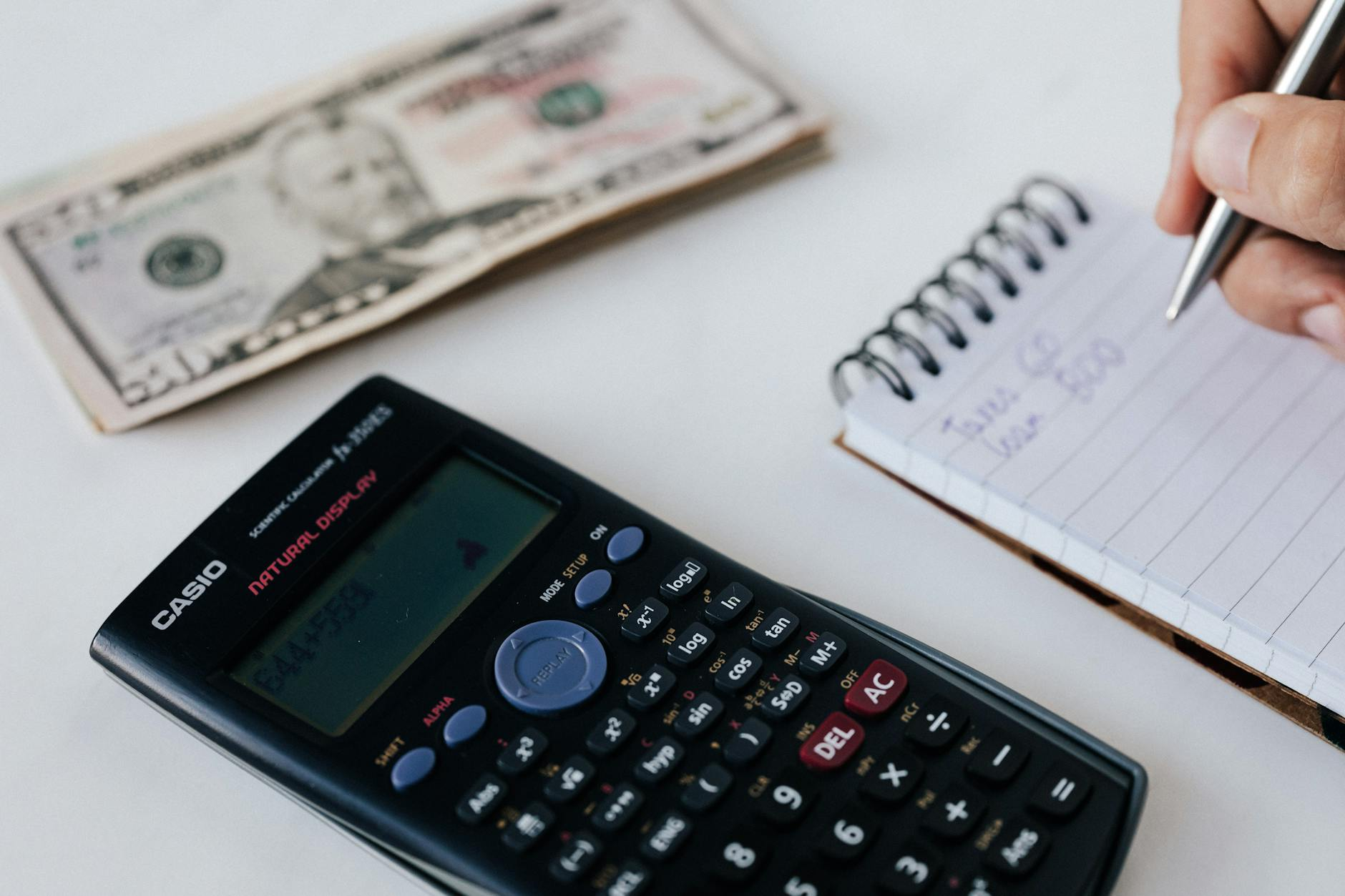 Notepad with TDEE calculations in kilojoules and kilocalories beside a calculator, kitchen scale, measuring tape, and a balanced meal of grilled chicken and vegetables on a sunlit kitchen counter