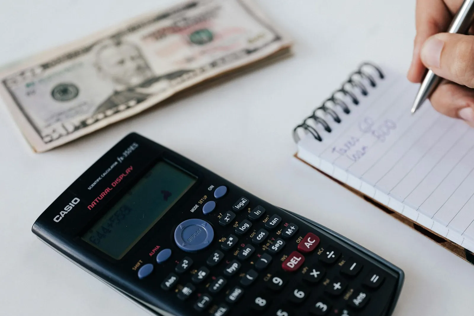 Notepad with TDEE calculations in kilojoules and kilocalories beside a calculator, kitchen scale, measuring tape, and a balanced meal of grilled chicken and vegetables on a sunlit kitchen counter