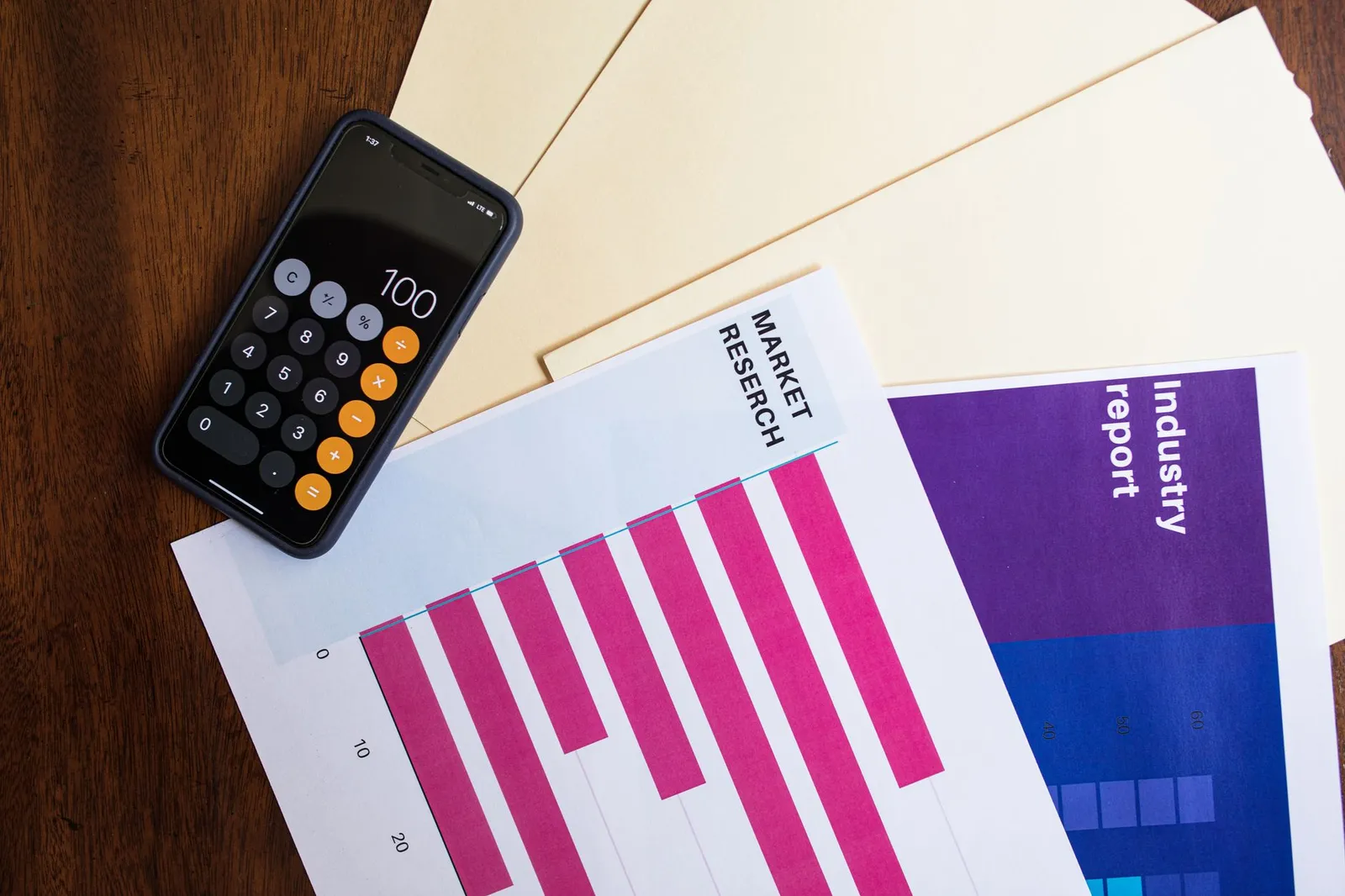A plate of grilled chicken, rice, and steamed vegetables beside a calculator, a printed macronutrient table, and a smartphone showing a calorie tracking app on a sunlit kitchen counter, illustrating the digestion cost behind the thermic effect of food