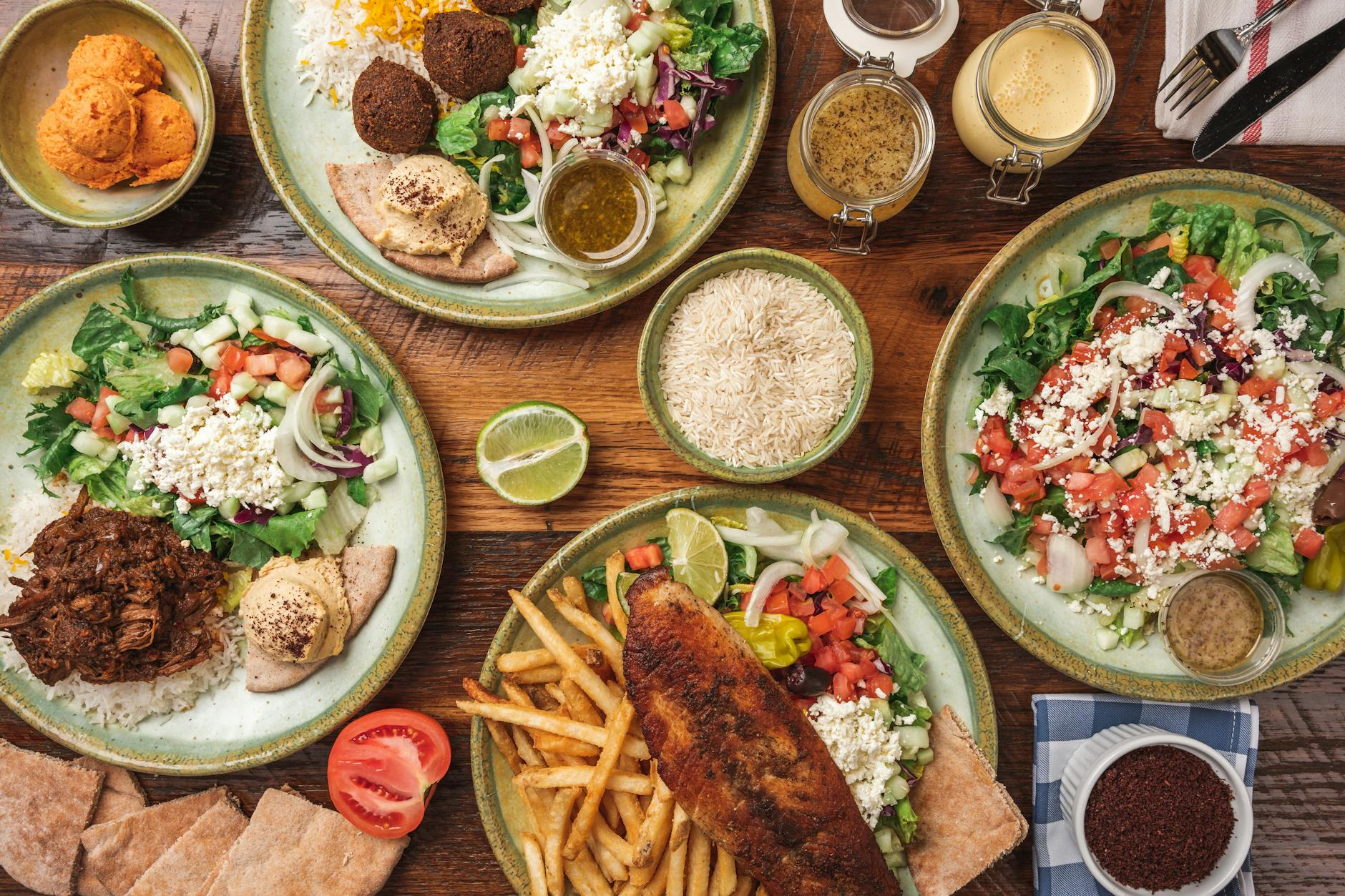 Colorful spread of global cuisine dishes including biryani, sushi rolls, tagine, tacos, and pho on a wooden table with diverse ingredients