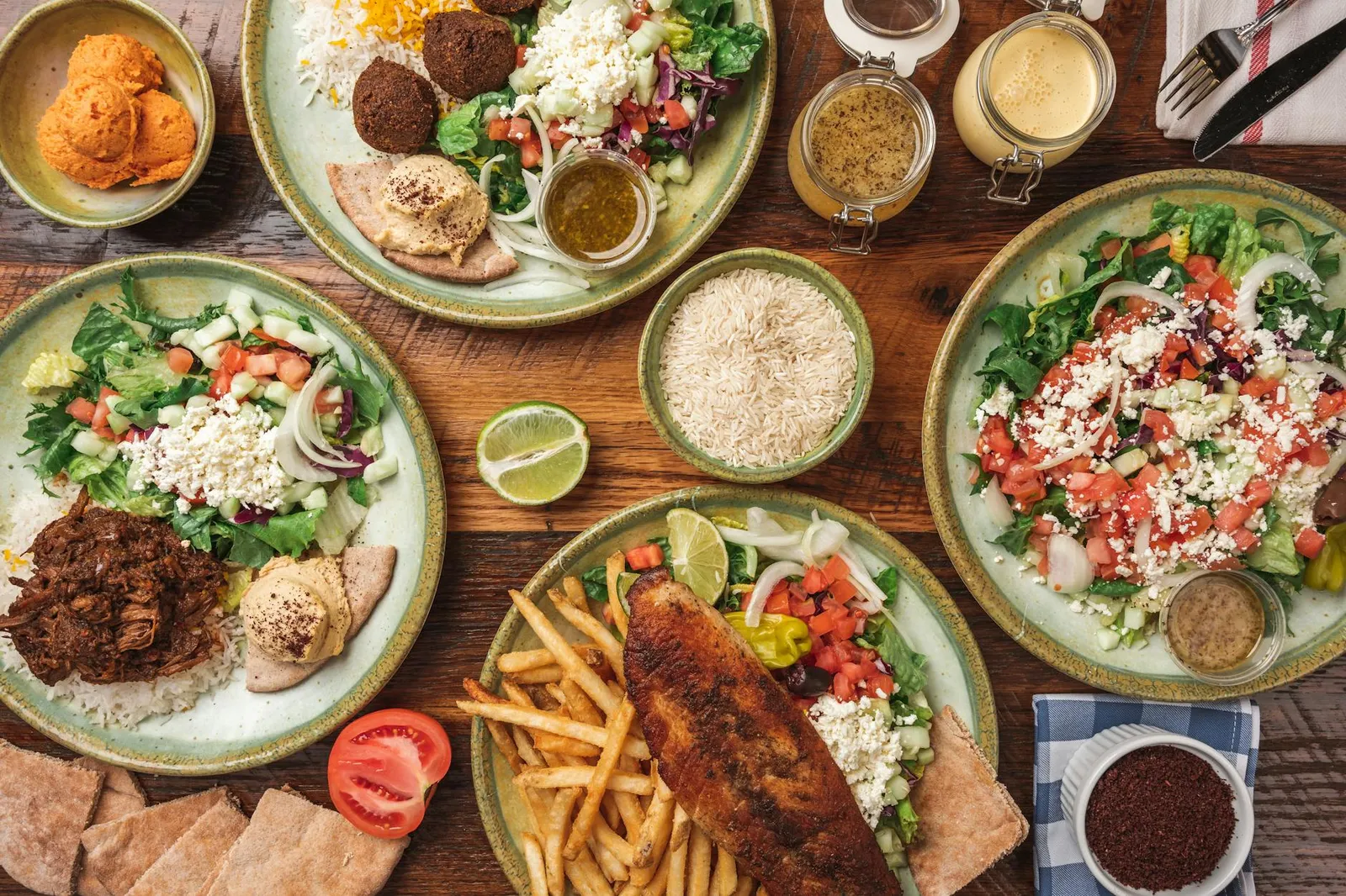 Colorful spread of global cuisine dishes including biryani, sushi rolls, tagine, tacos, and pho on a wooden table with diverse ingredients